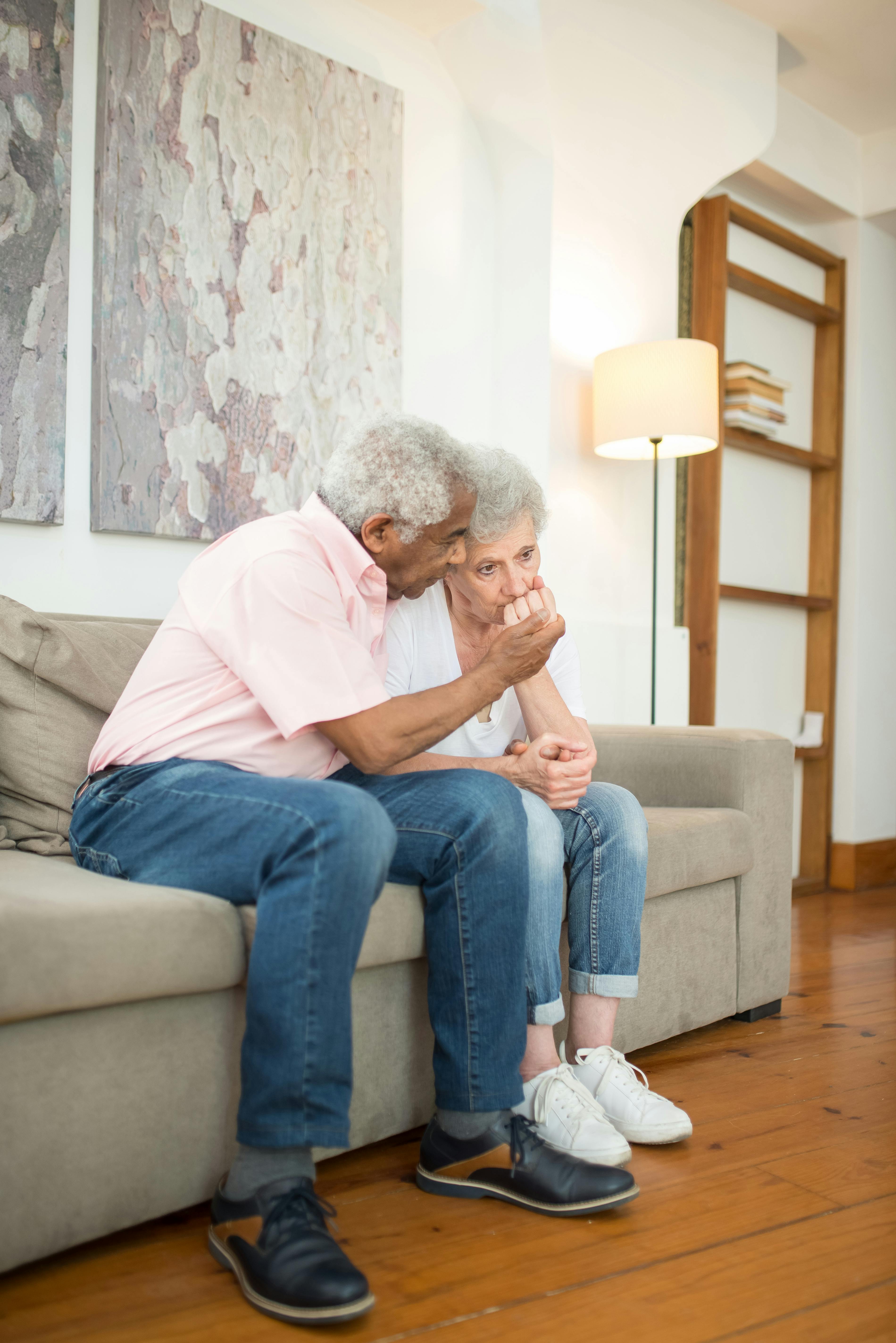 A sad older couple sitting on a couch | Source: Pexels