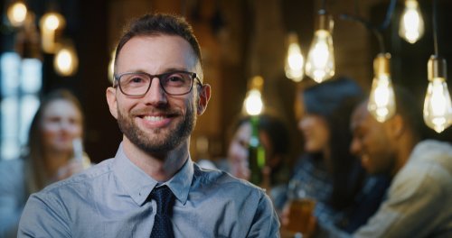 Man at a bar smiling broadly at the bartender. | Source: Shutterstock.
