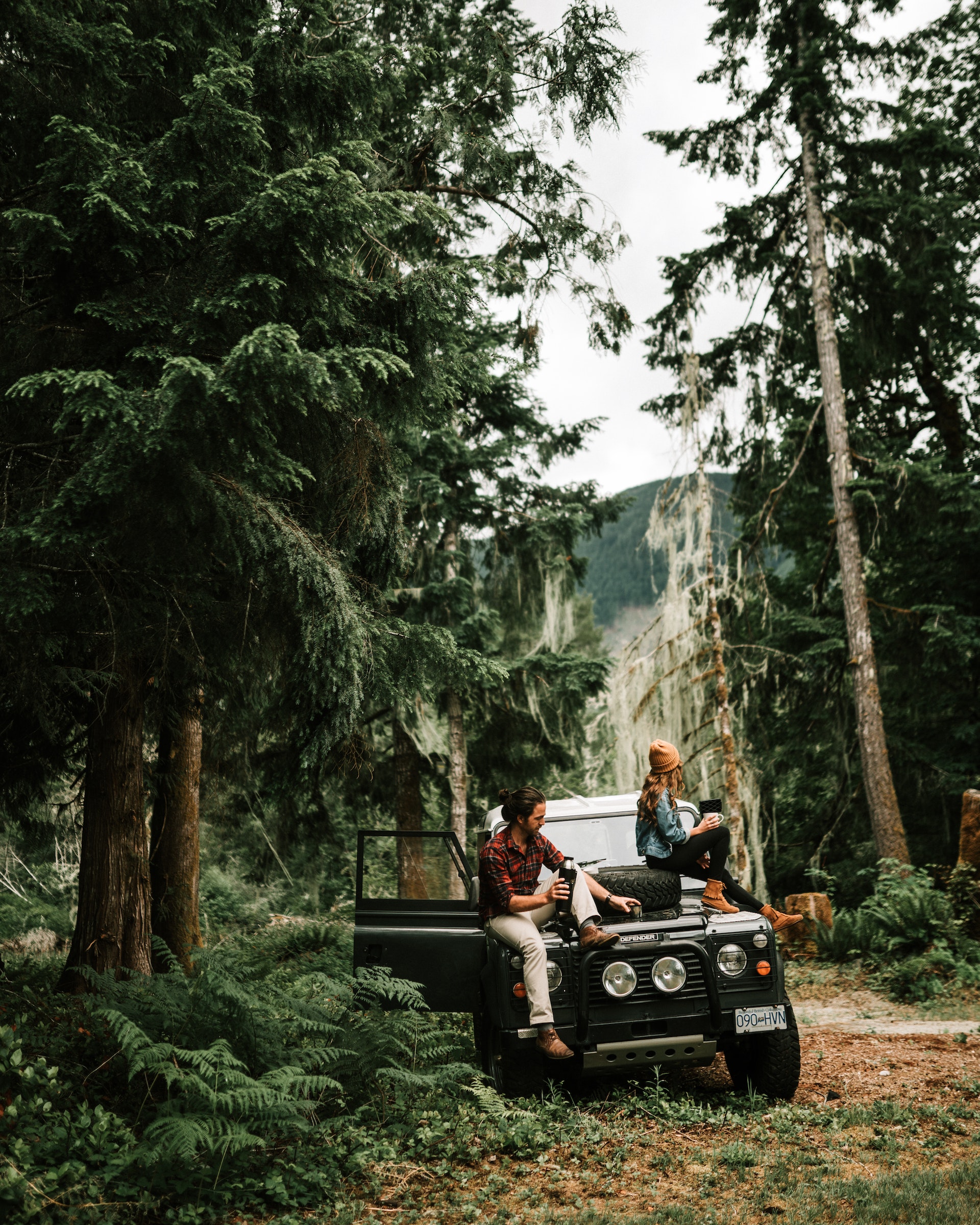 A couple sitting on a jeep in the middle of a forest | Source: Pexels