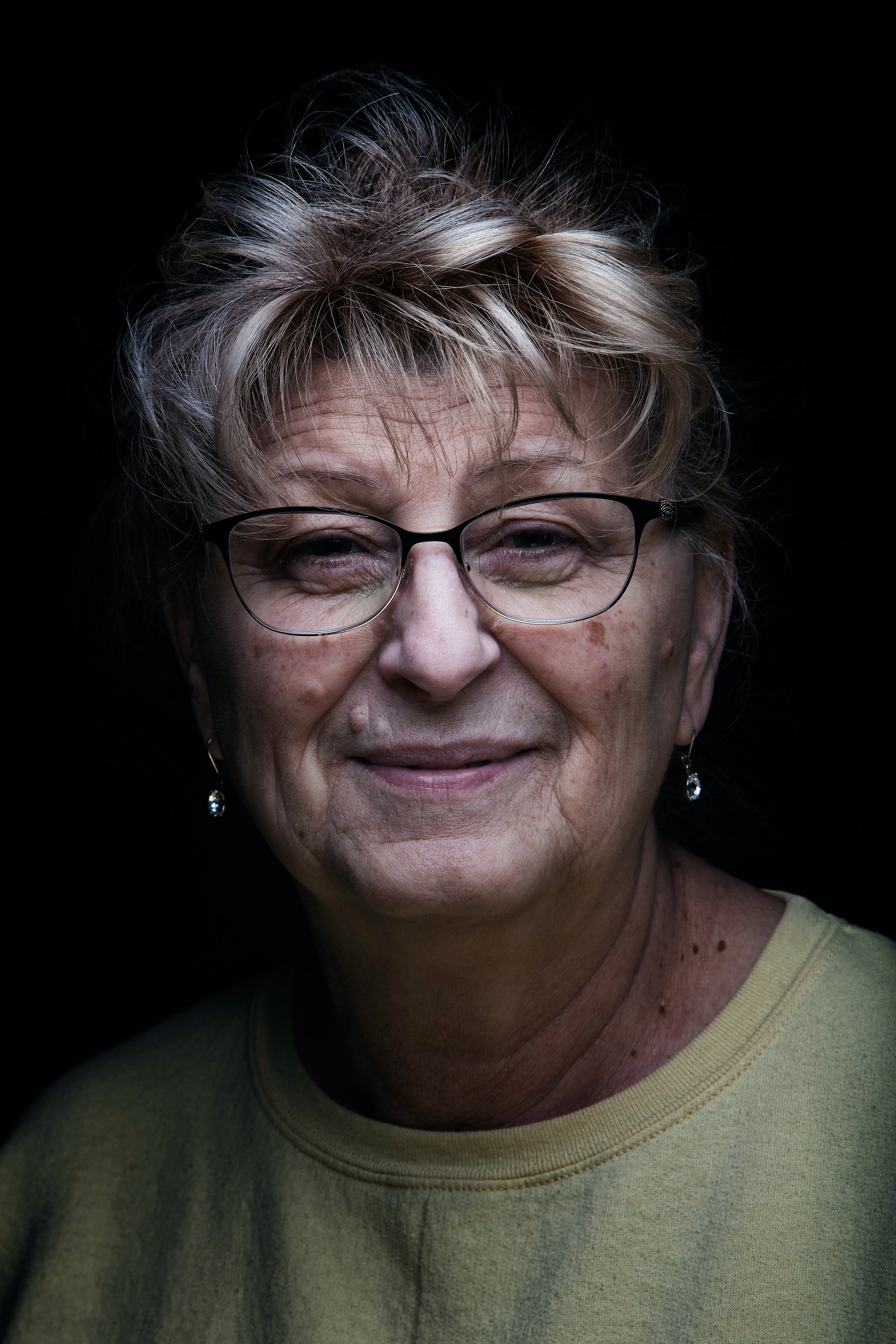 Una mujer mayor con anteojos sonriendo. | Foto: Unsplash