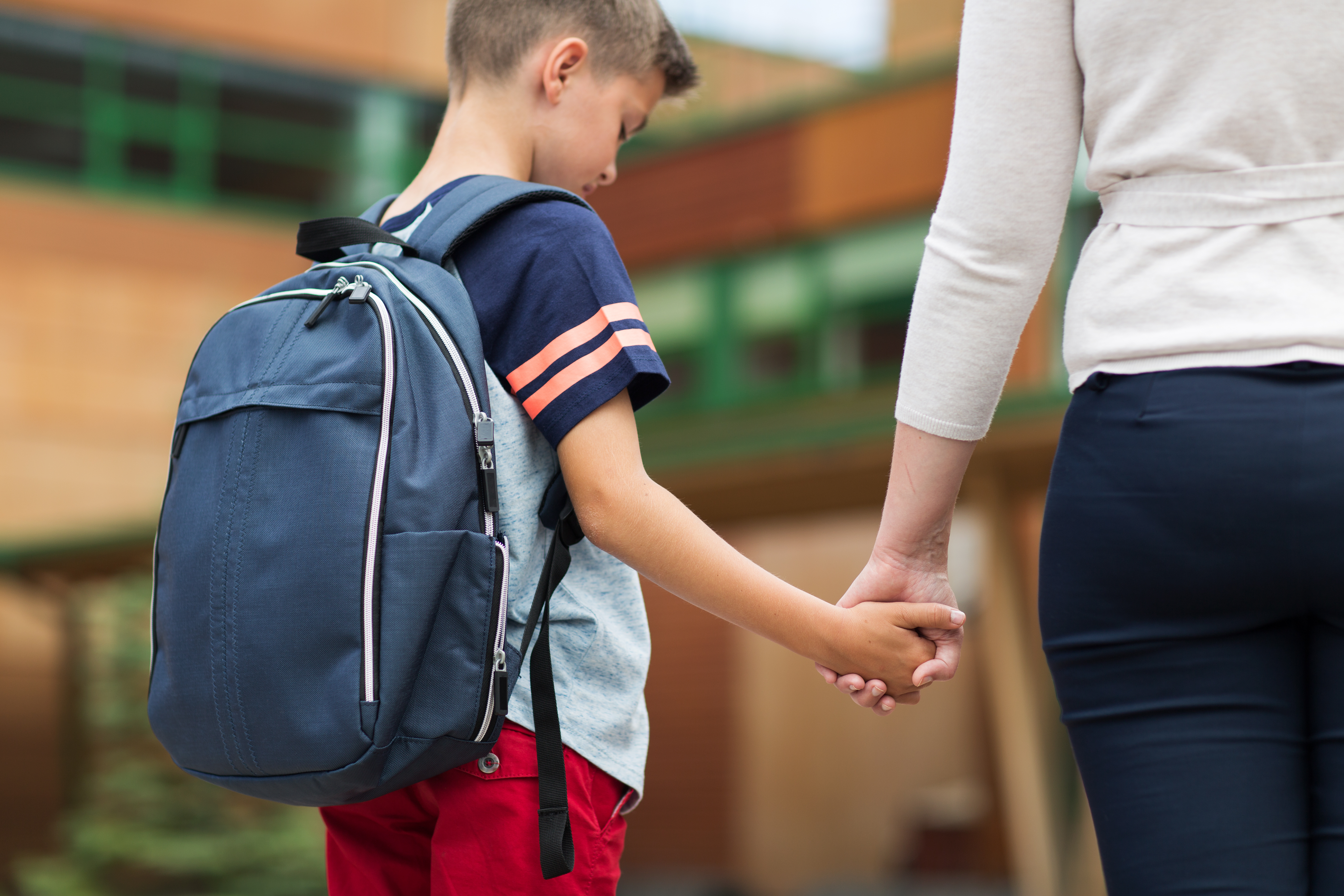 Sad elementary student boy with mother at school yard. | Source: Shutterstock