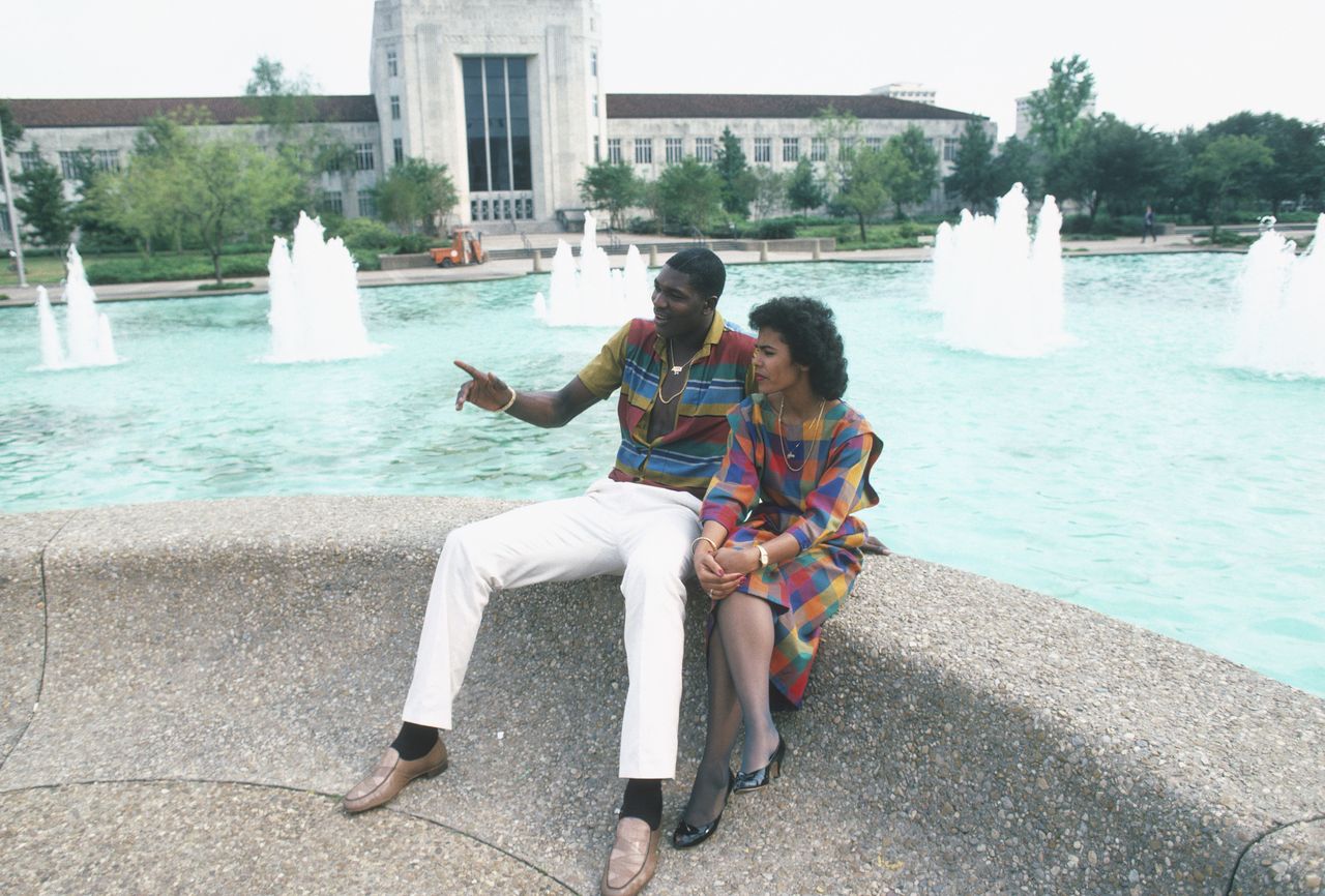 Hakeem Olajuwon poses for a photo with his wife in front of a fountain in Houston, Texas.| Source: Getty Images