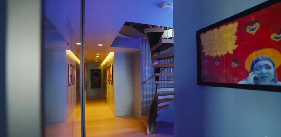 Seen from below, the staircase looks almost like an art installation tucked into the family's gallery-like lower level. It became the elegant answer to a very basic problem: the two floors originally were not connected at all. | Source: YouTube/Architectural Digest