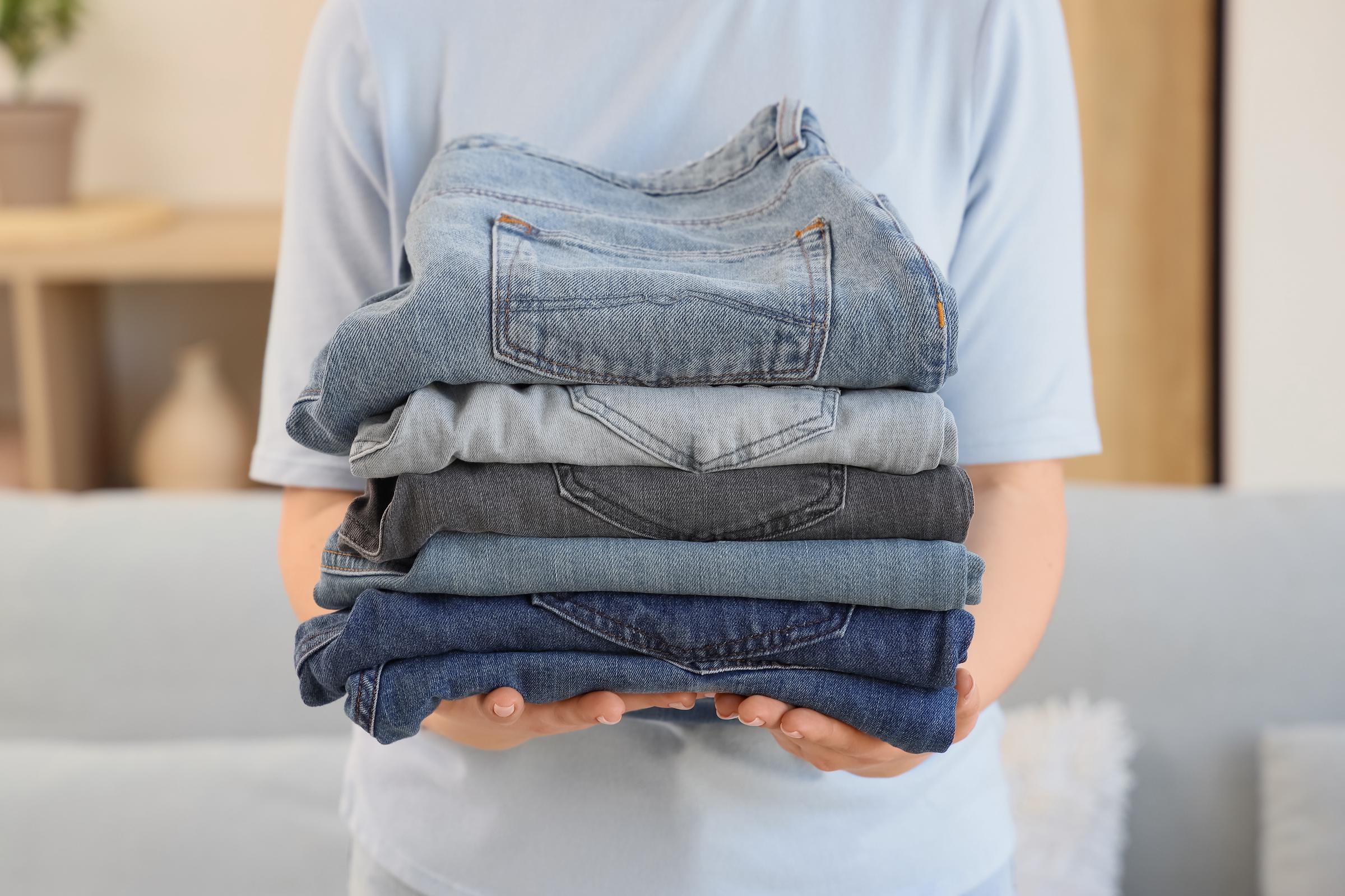 Woman holding a pile of folded jeans | Source: Getty Images