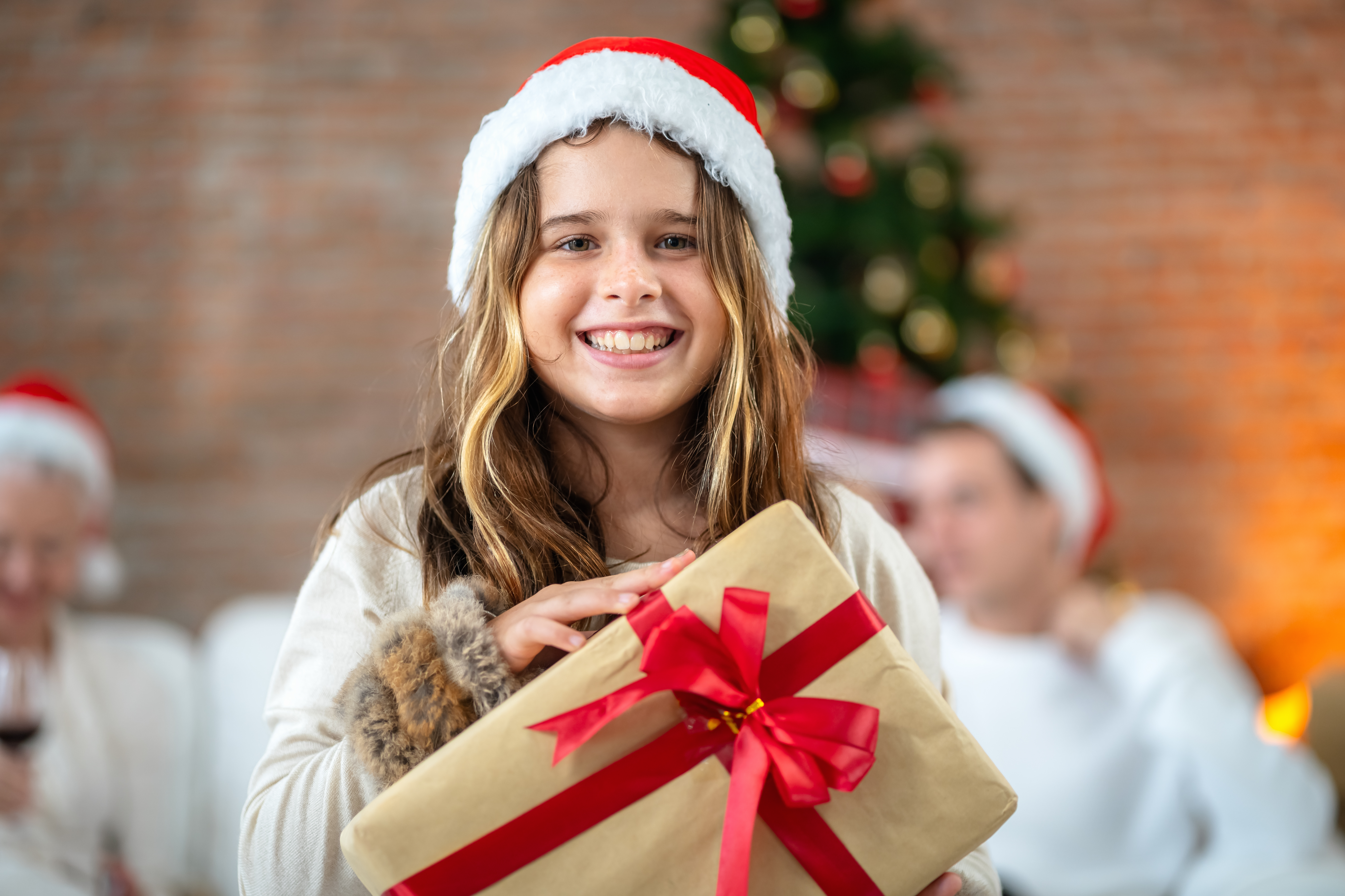 A young girl holding a gift box smiles happily on Christmas Day. | Source: Getty Images
