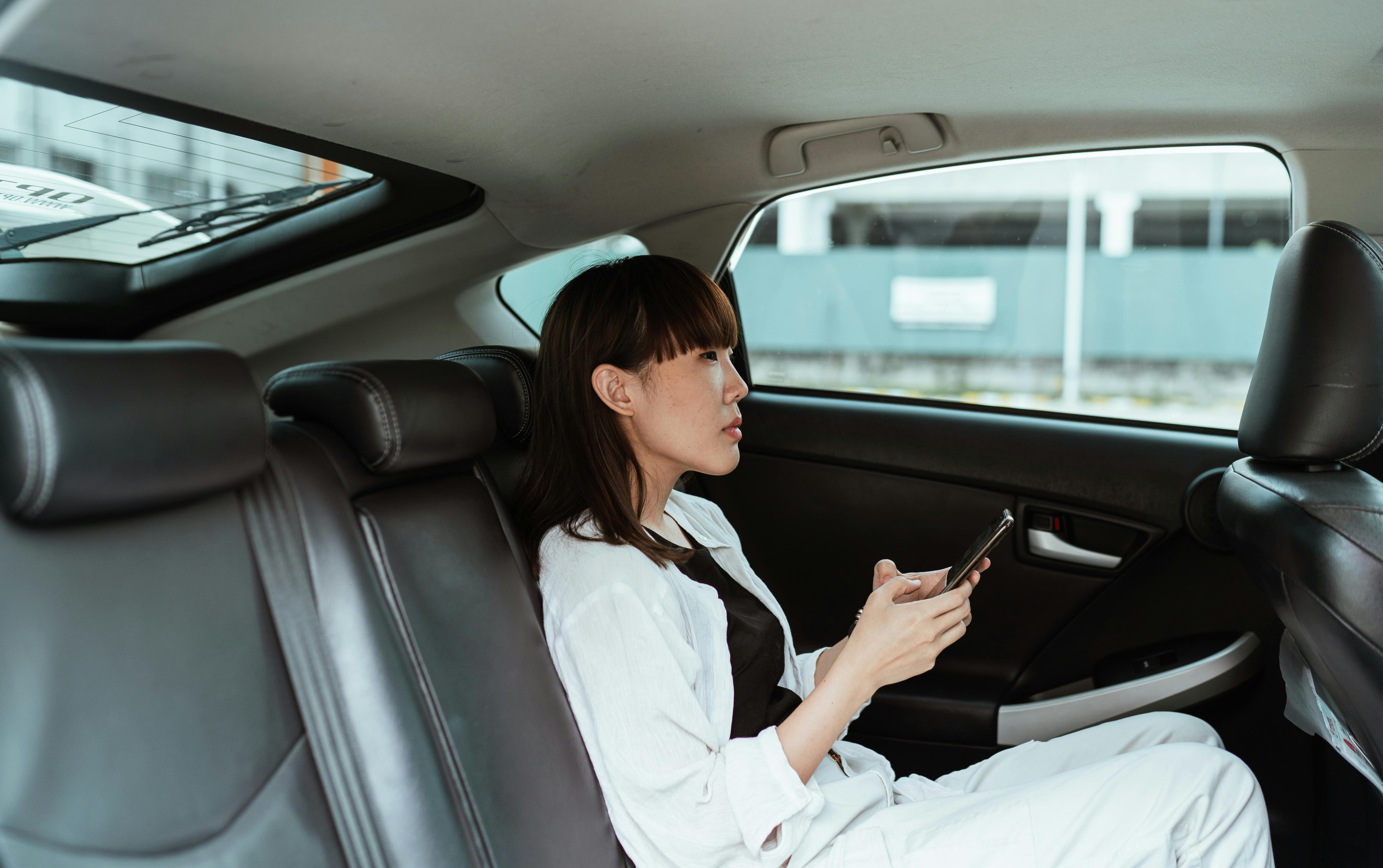 Disappointed woman seated in her car using her phone | Source: Pexels