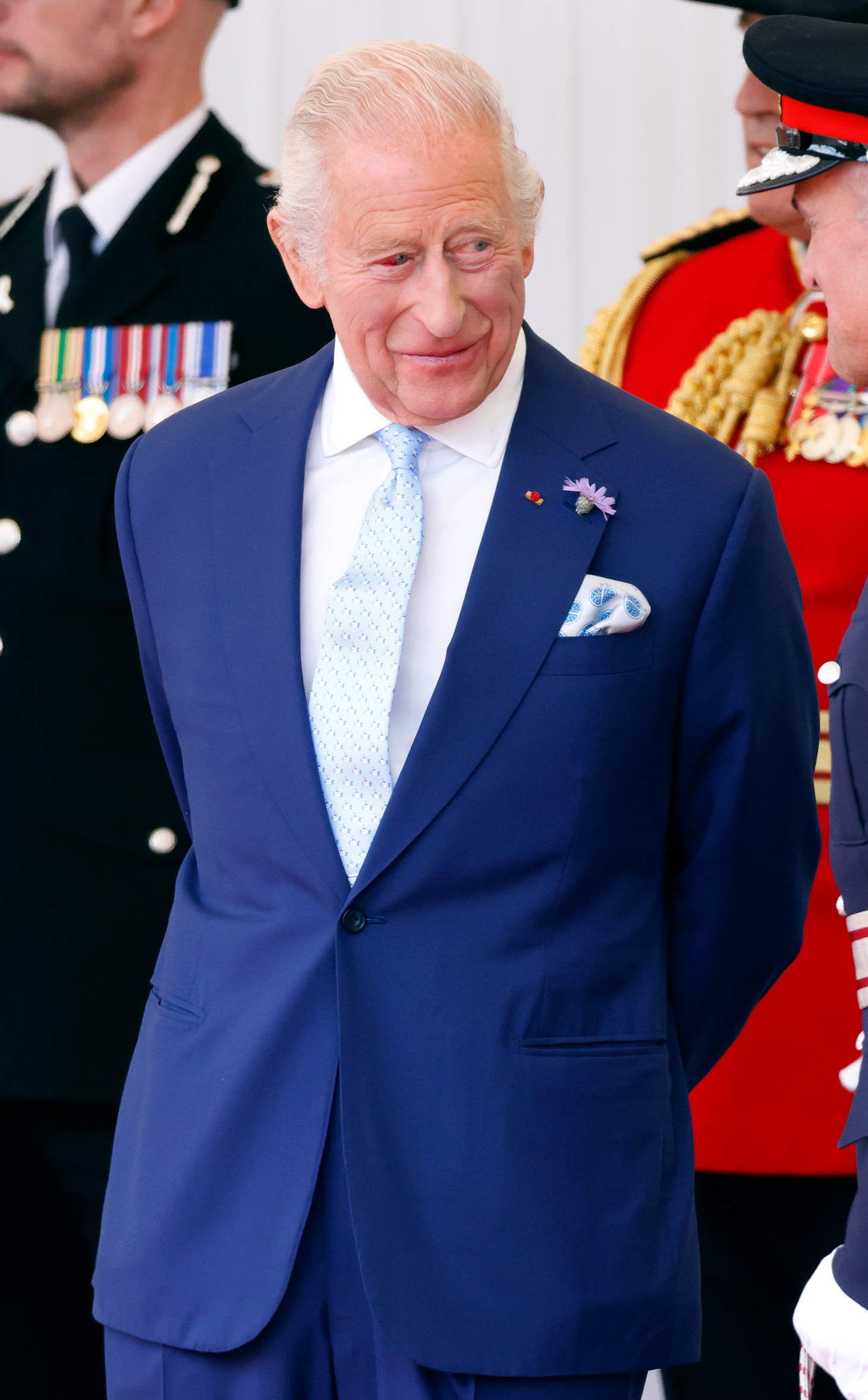 King Charles III is seen standing with officials at the Royal Dais. Despite a bloodshot eye, the monarch appears composed during the Macrons' historic state visit — France's first in 17 years.