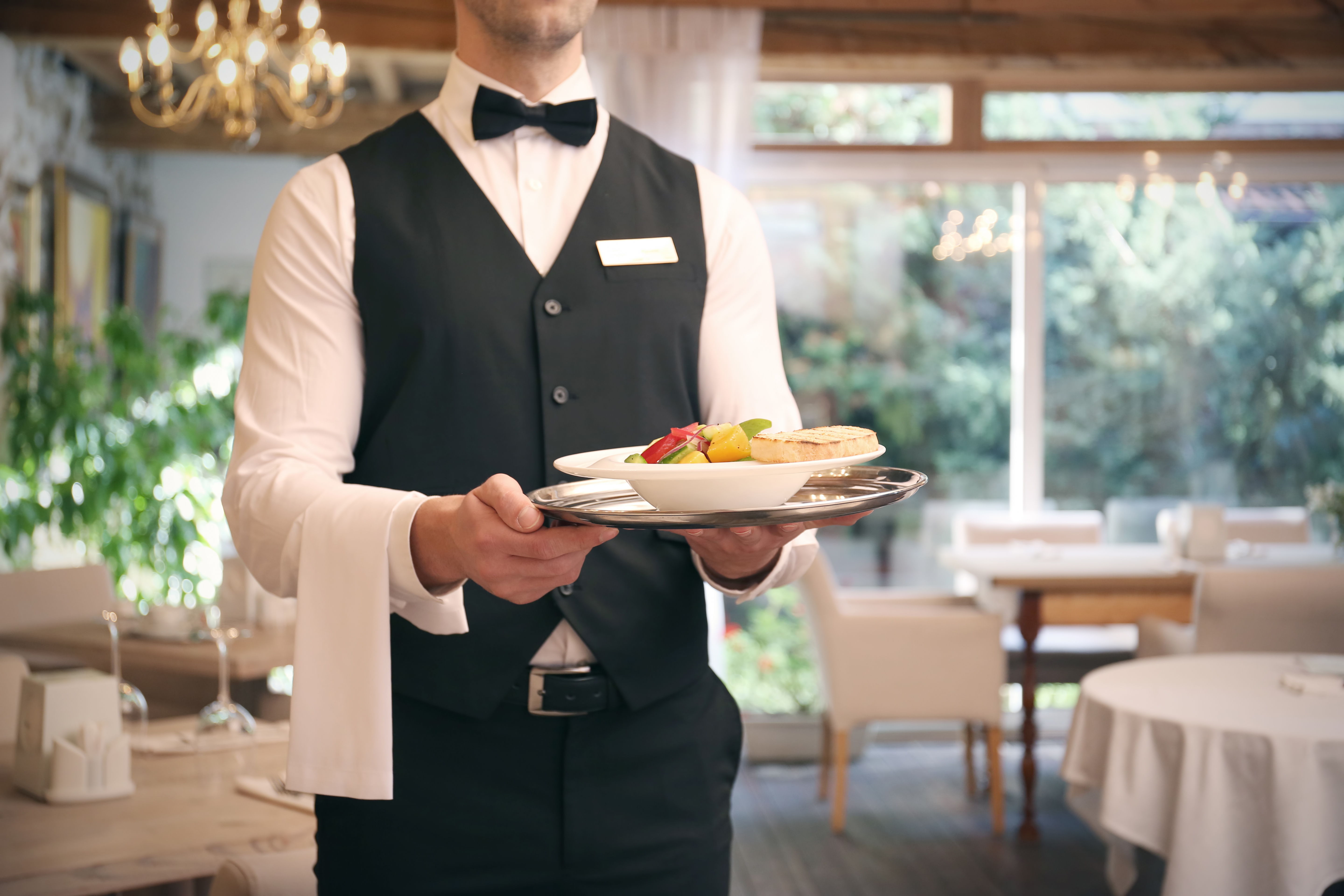 A waiter serves the food in the restaurant | Source: Shutterstock