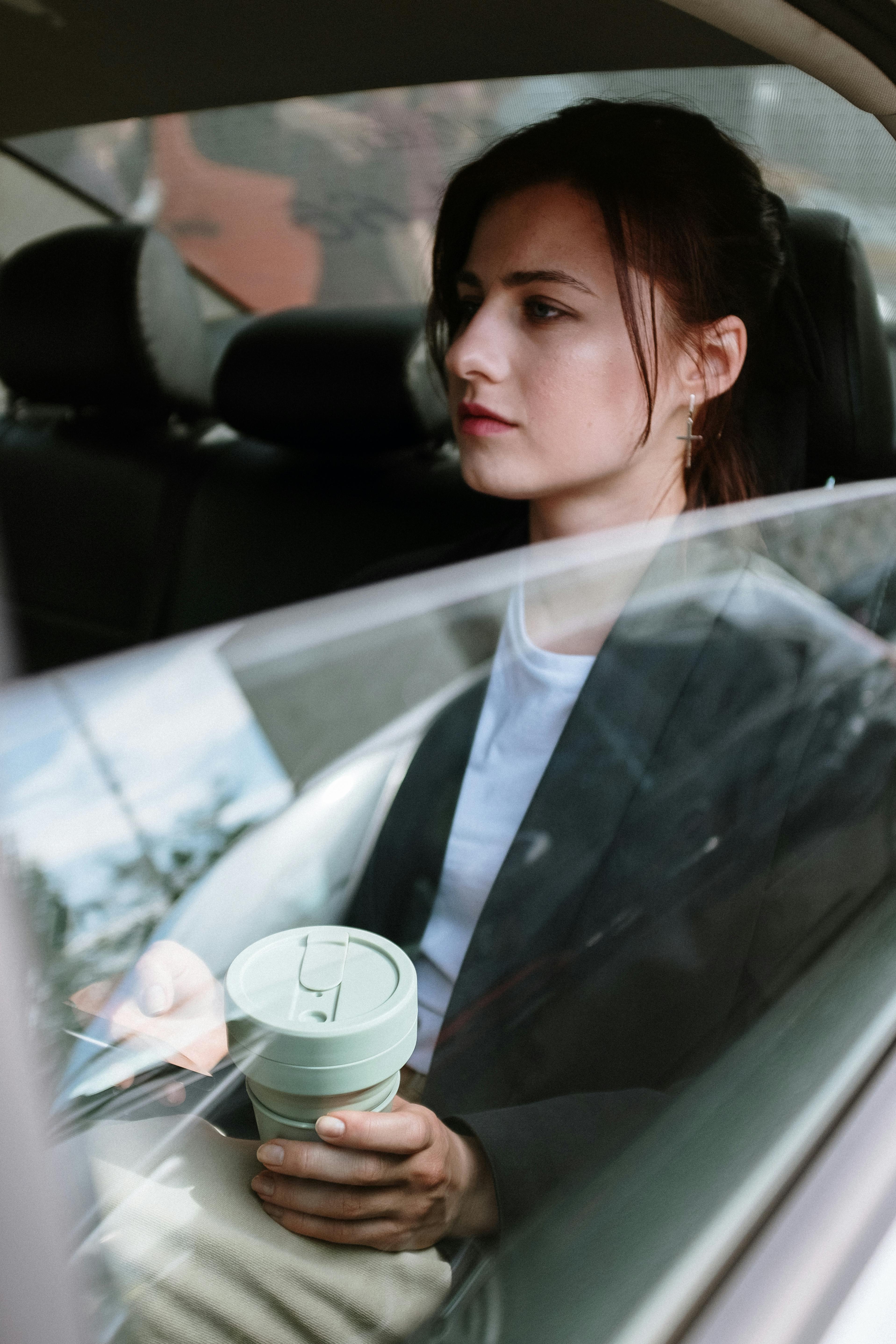 Une femme sérieuse assise à l'arrière d'une voiture | Source : Pexels