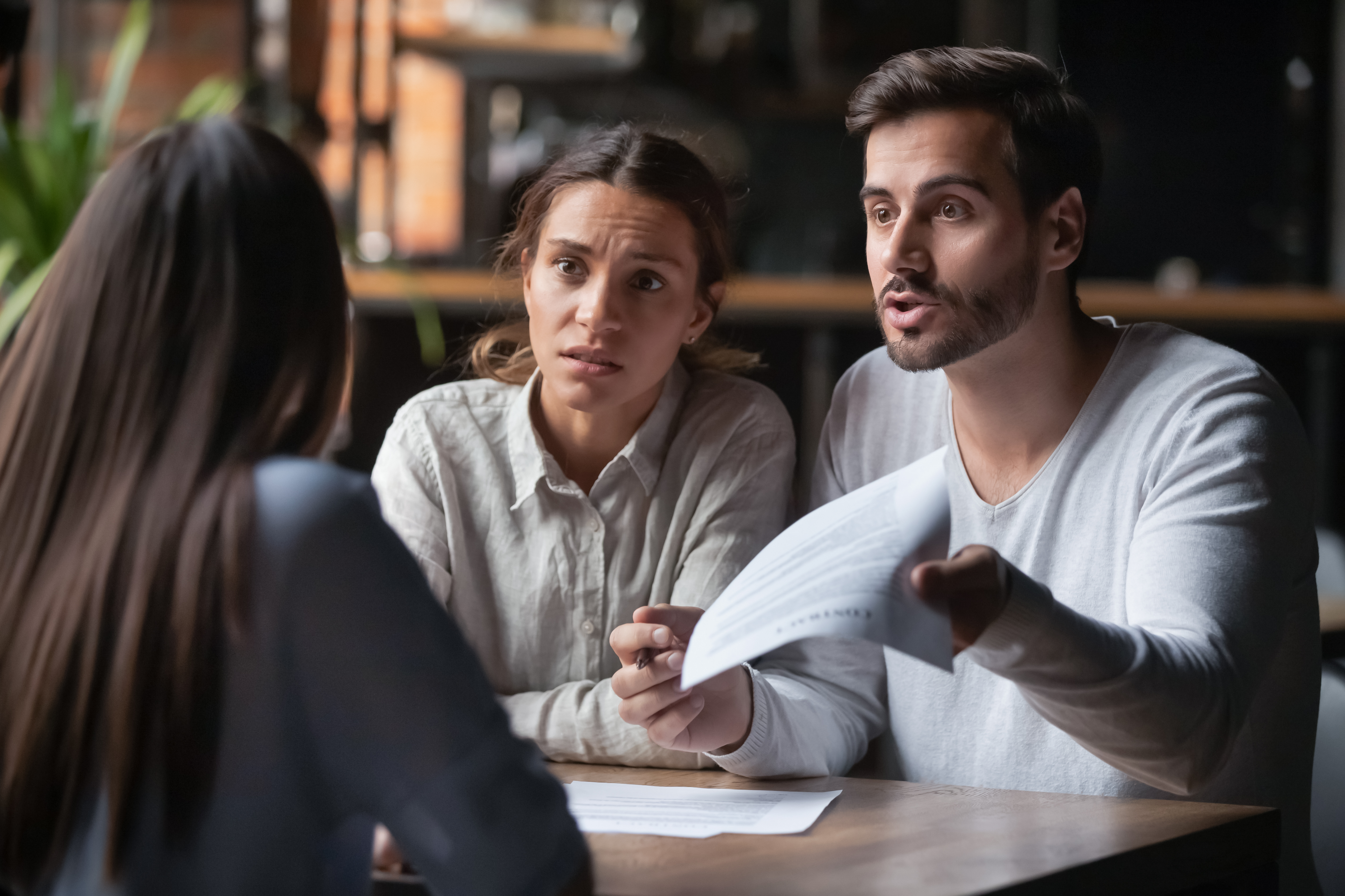 Una pareja molesta hablando con una mujer mientras el hombre le hace un gesto con unos documentos |  Fuente: Shutterstock