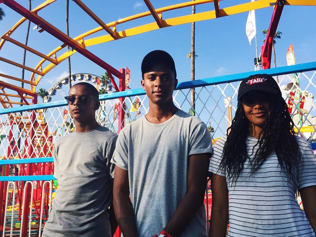 Blake Underwood (left) stands with his brother Paris Underwood and sister Brielle Underwood at an outdoor fair, posing together with colorful rides in the background. | Source: Instagram/brielleunderwood