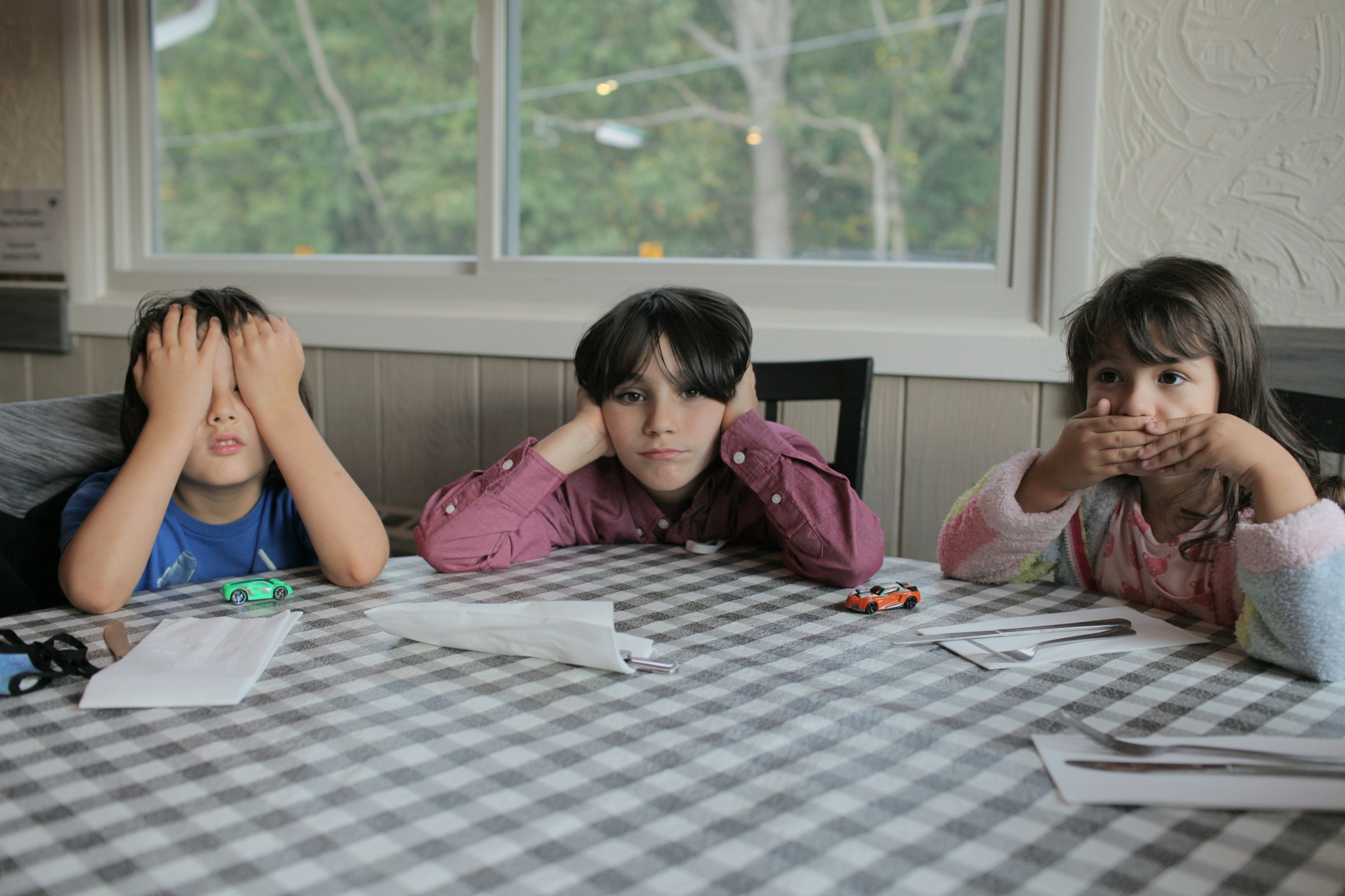 Three kids sitting on a table | Source: Unsplash