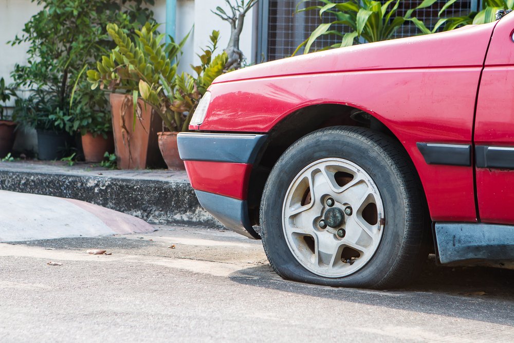 Voiture avec un pneu crevé. | Photo : Shutterstock