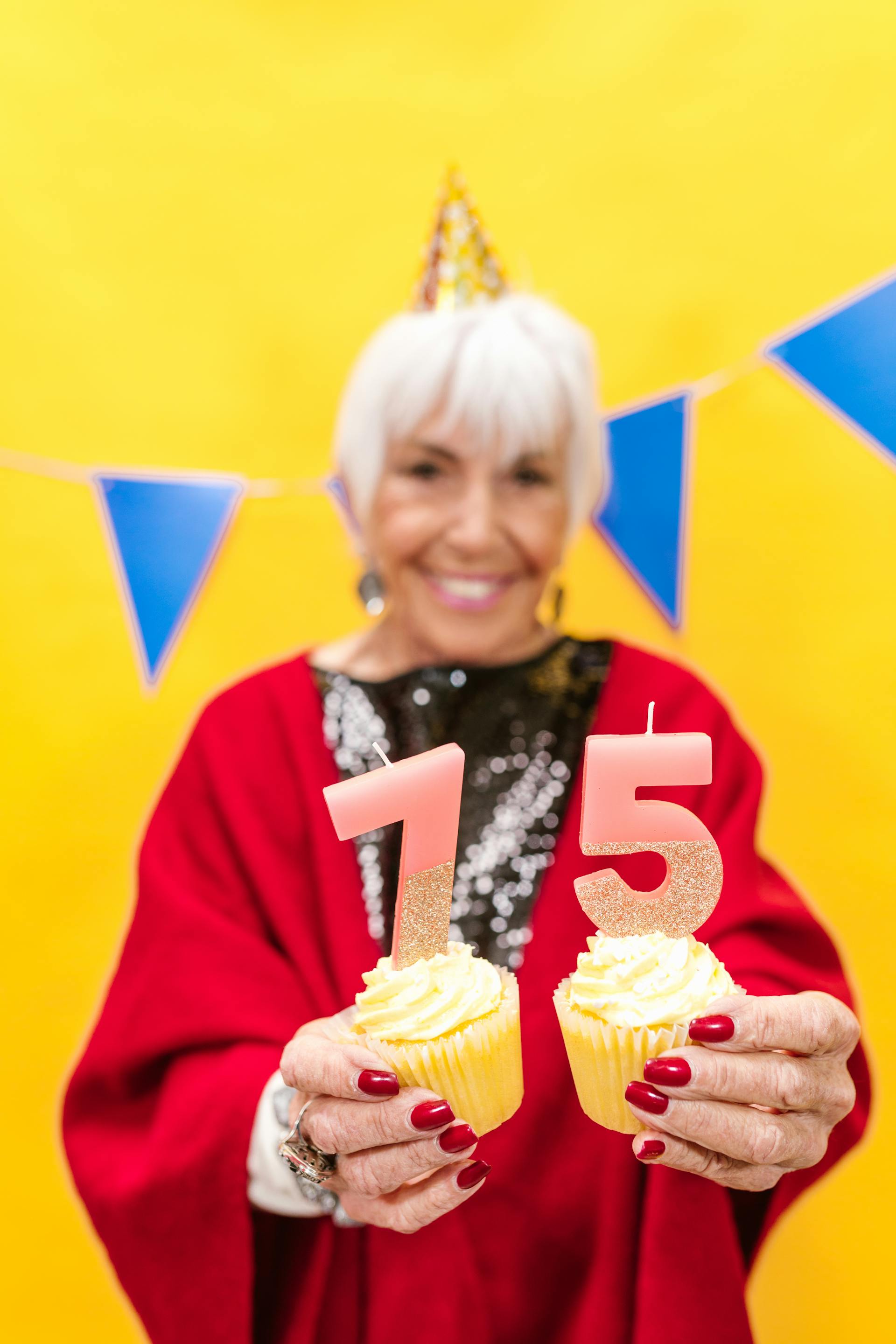 An elderly woman holding cupcakes on her birthday | Source: Pexels