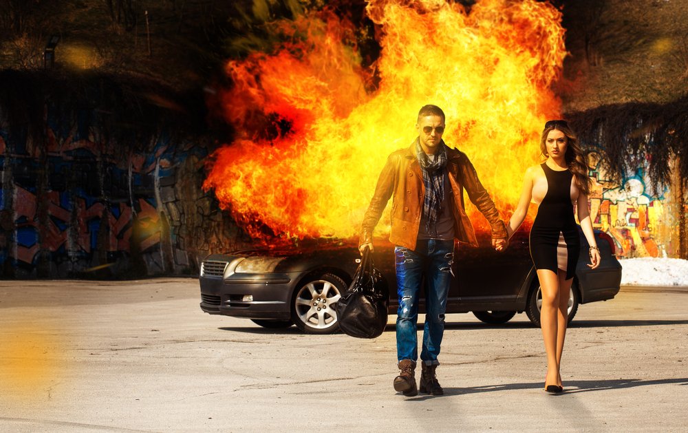 Pareja alejándose de un automóvil quemado. | Foto: Shutterstock