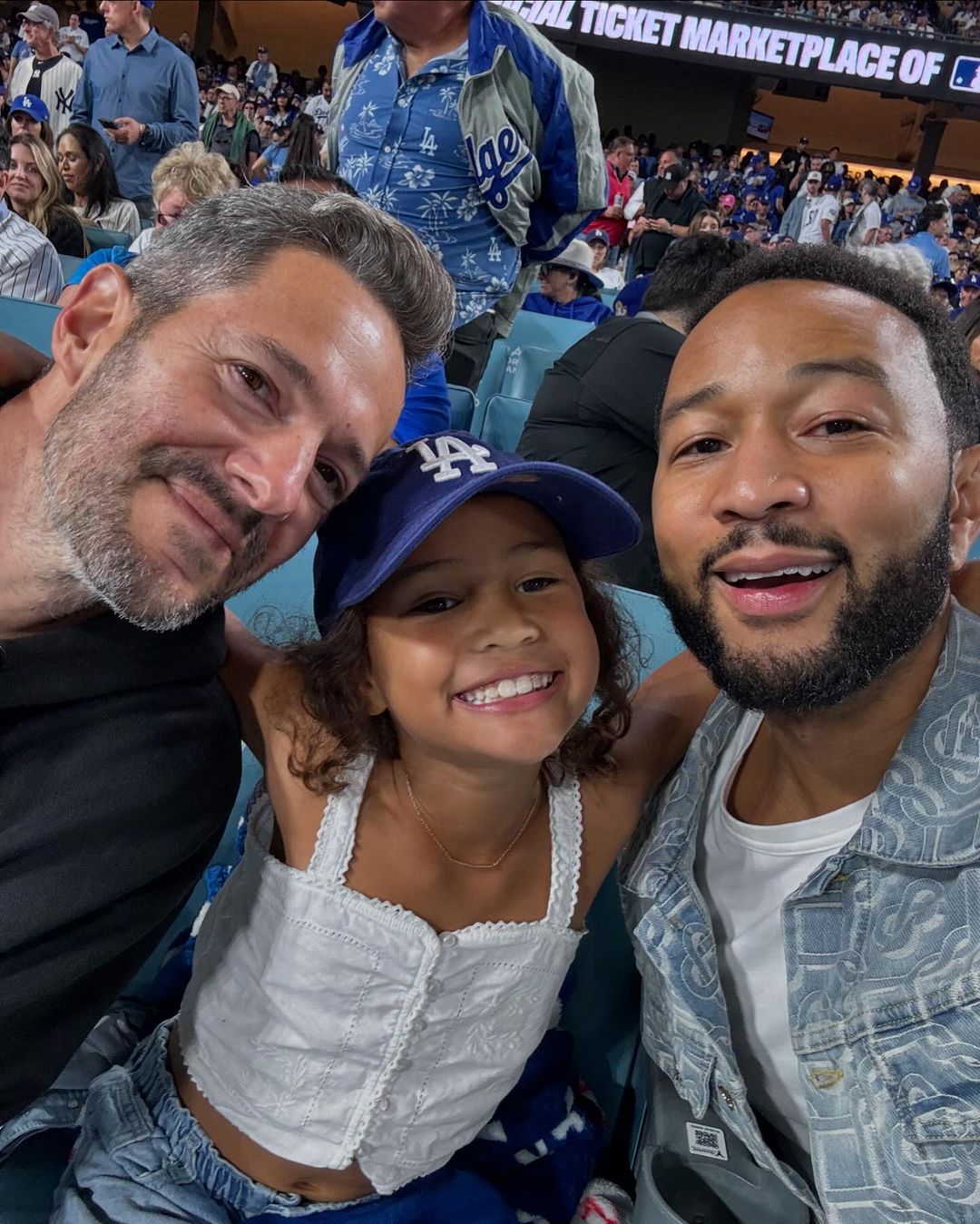 A friend, Luna, and John Legend at the pivotal Game 1 between the Dodgers and the Yankees at the World Series, from a post dated October 26, 2024 | Source: Instagram/johnlegend/