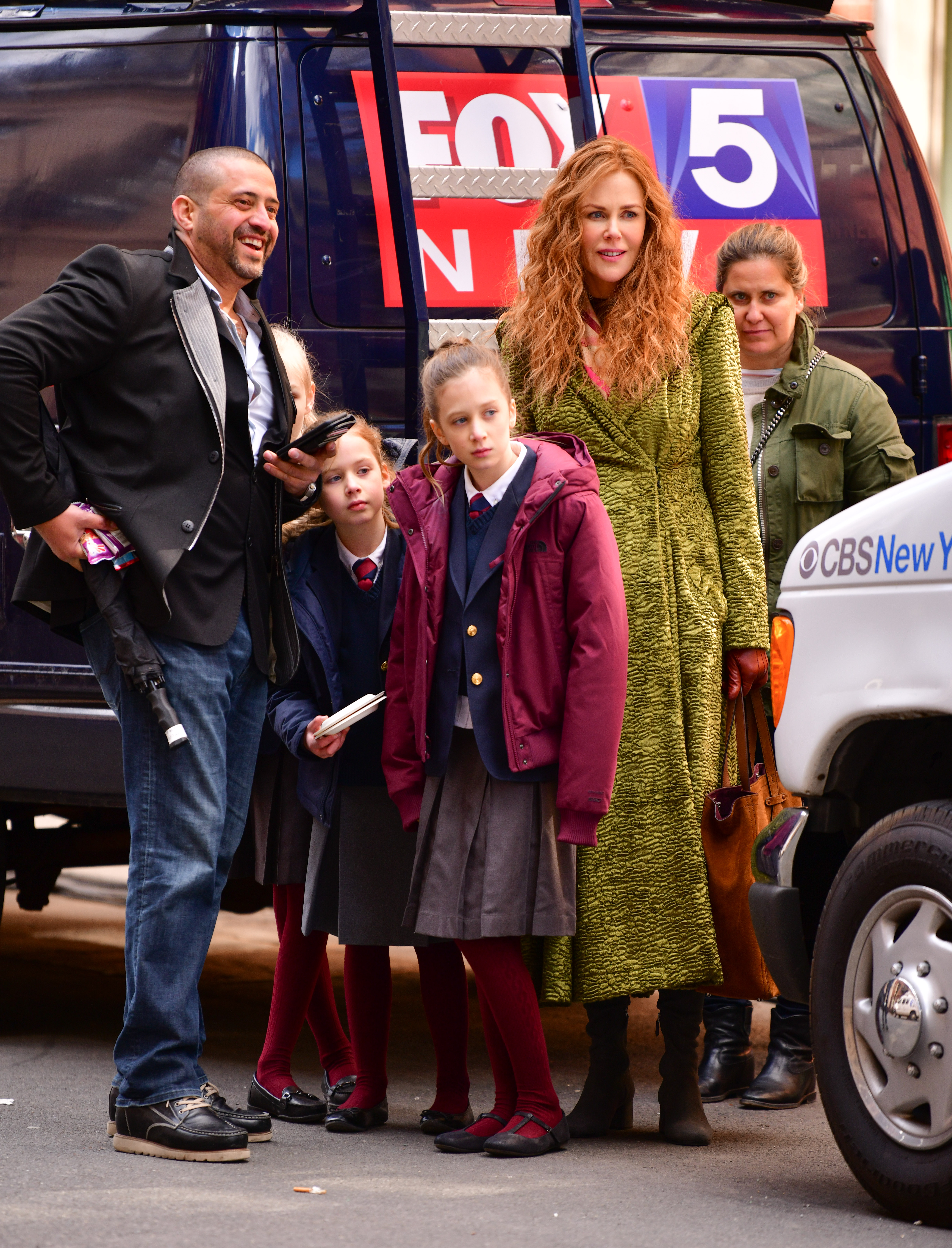 Nicole Kidman stands alongside her daughters, Faith Margaret and Sunday Rose, while filming scenes for "The Undoing" on New York's Upper East Side, on March 19, 2019. The actress, wearing a textured green coat and gloves, appears on set with crew members as her daughters, dressed in matching school uniforms, watch the production closely.