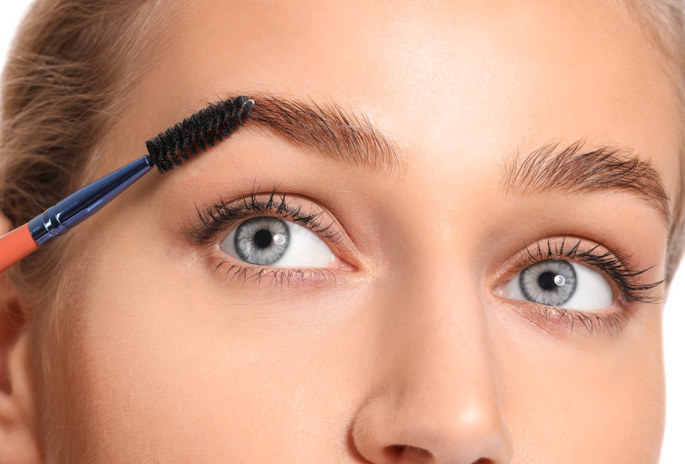 Primer plano de una mujer cepillando sus cejas. | Foto: Shutterstock