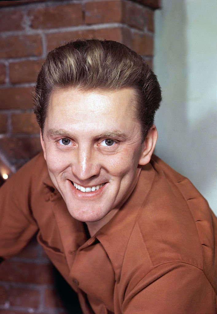 Kirk Douglas smiles for the camera in front of a brick wall backdrop, on January 1, 1960 | Source: Sunset Boulevard/Corbis via Getty Images