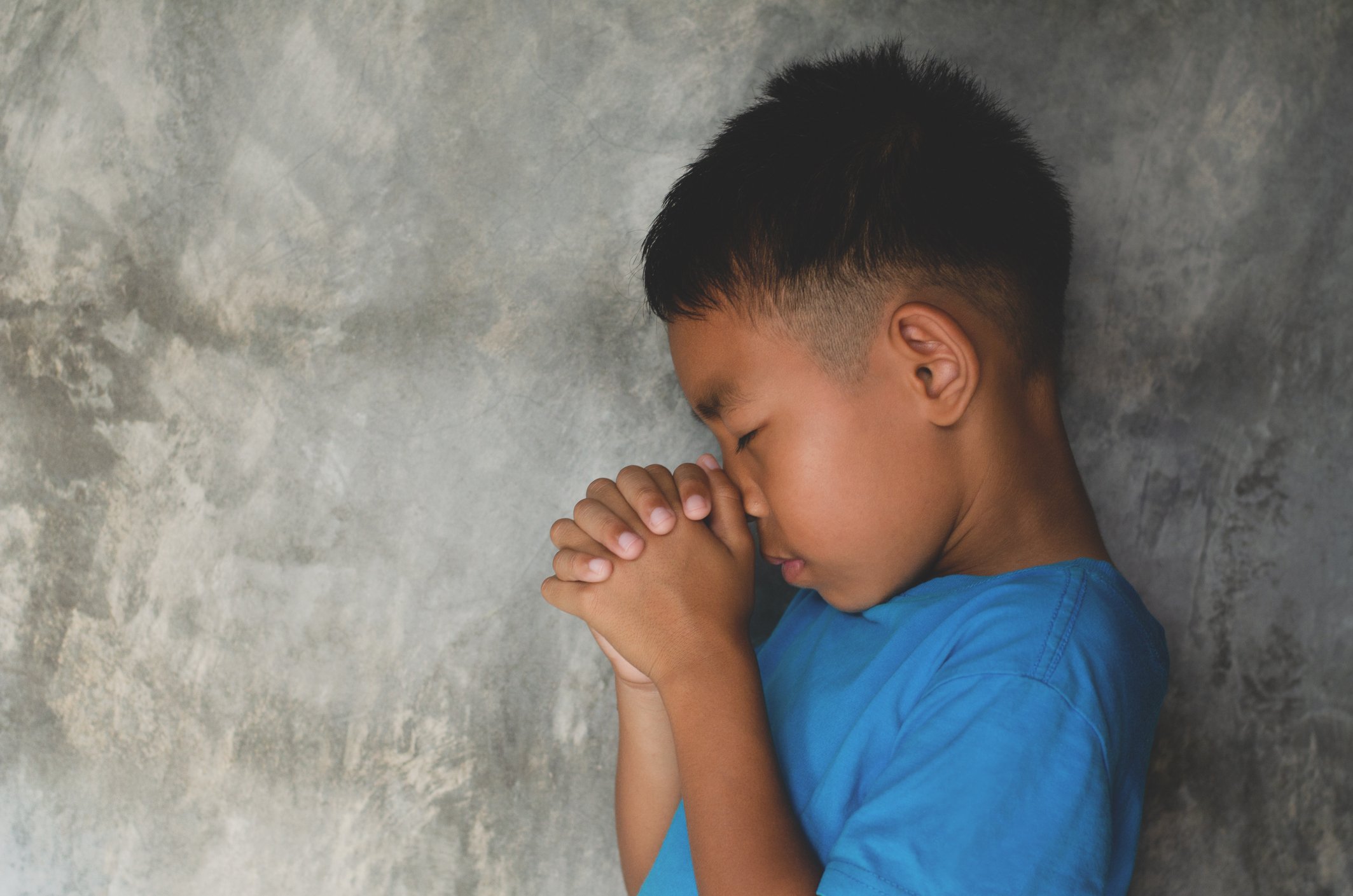 Side View Of Boy Praying By Wall |Photo: Getty images