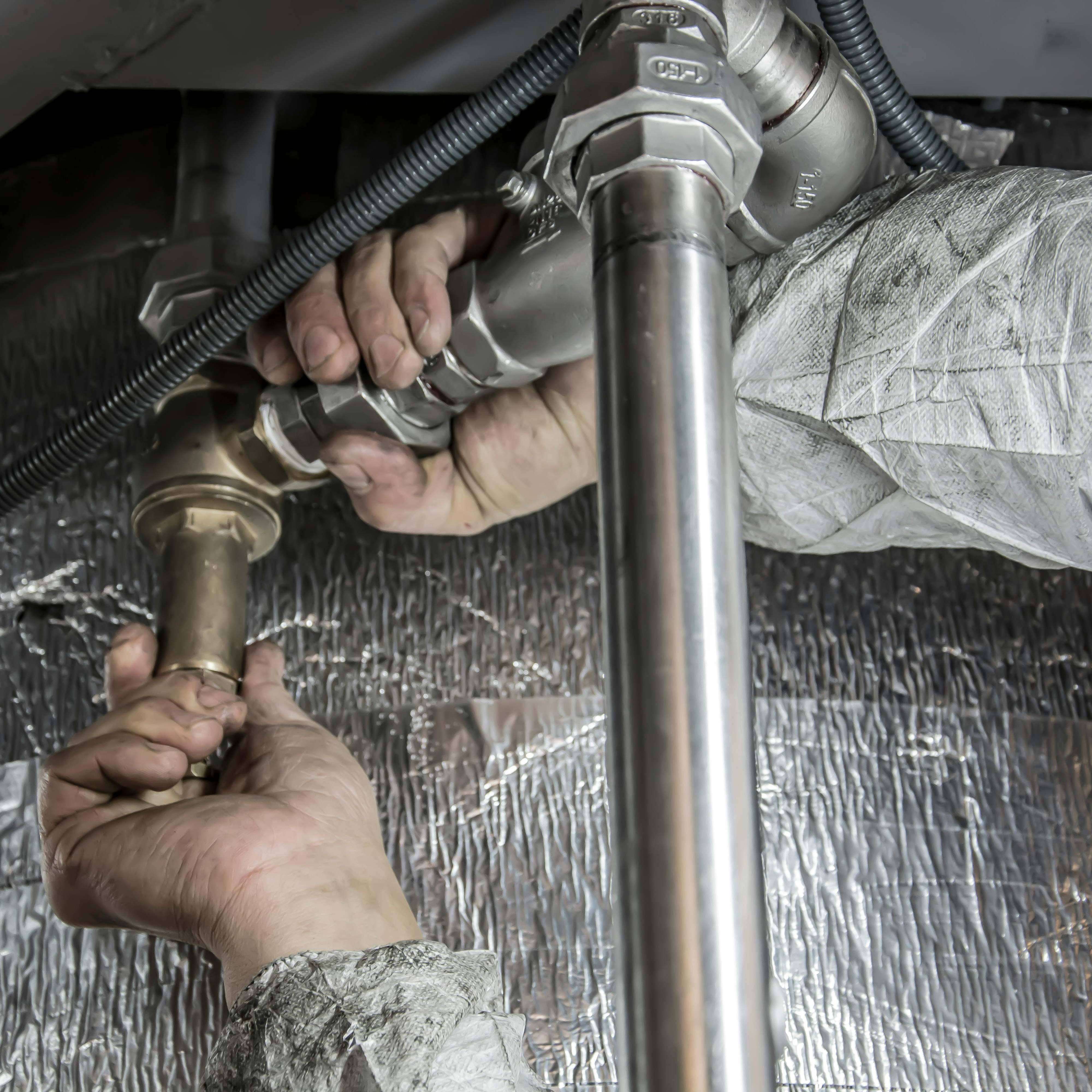 A pair of hands working on a pipe junction | Source: Pexels