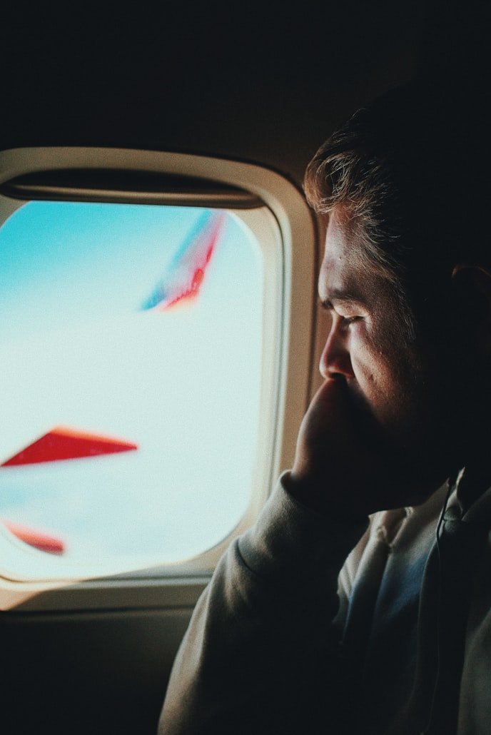 Un hombre joven mira por la ventanilla de un avión. | Foto: Unsplash