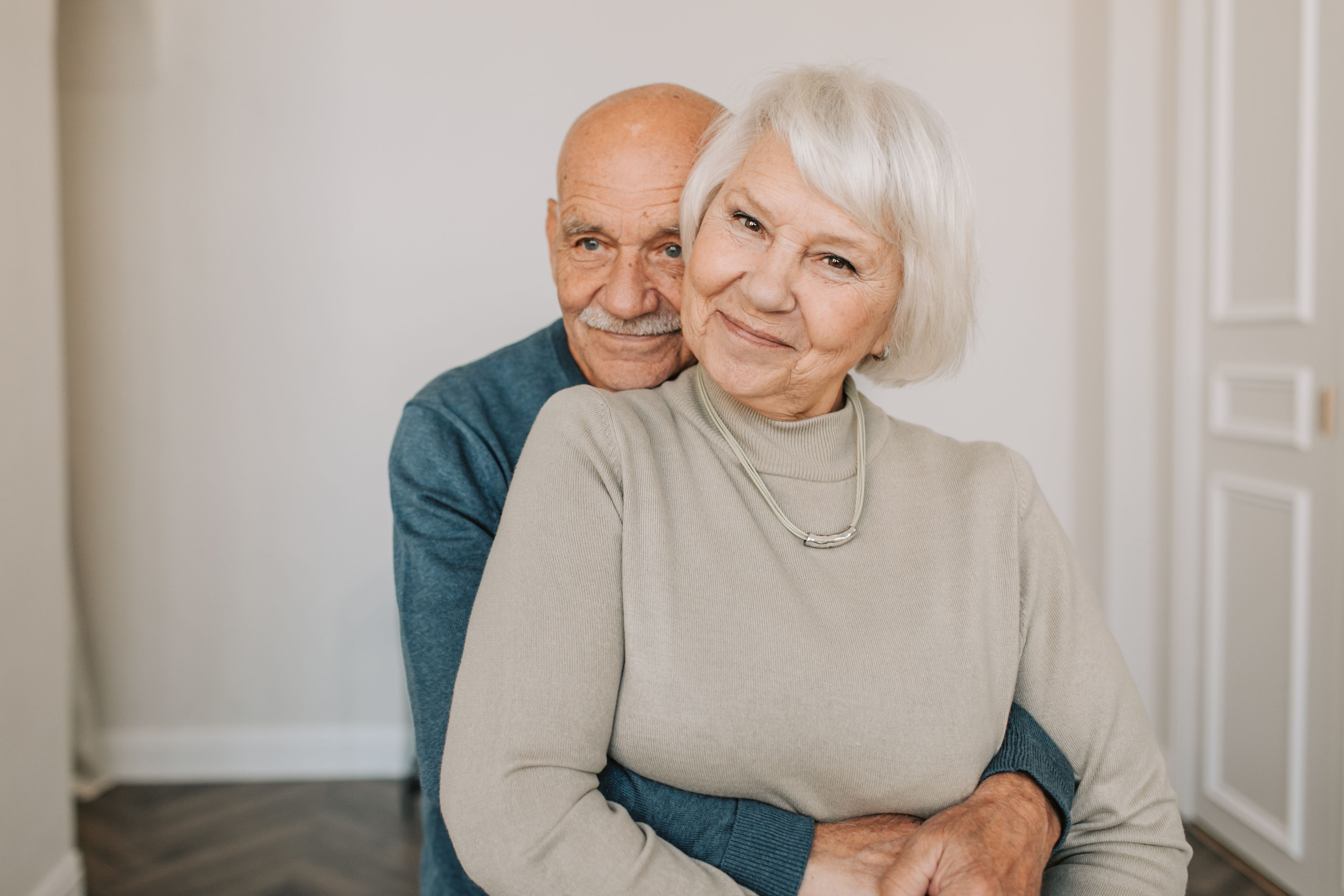 An older couple smiles while embracing inside their home. | Source: Pexels