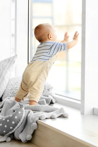 Un bébé qui s'appuie sur la fenêtre | Photo : Shutterstock