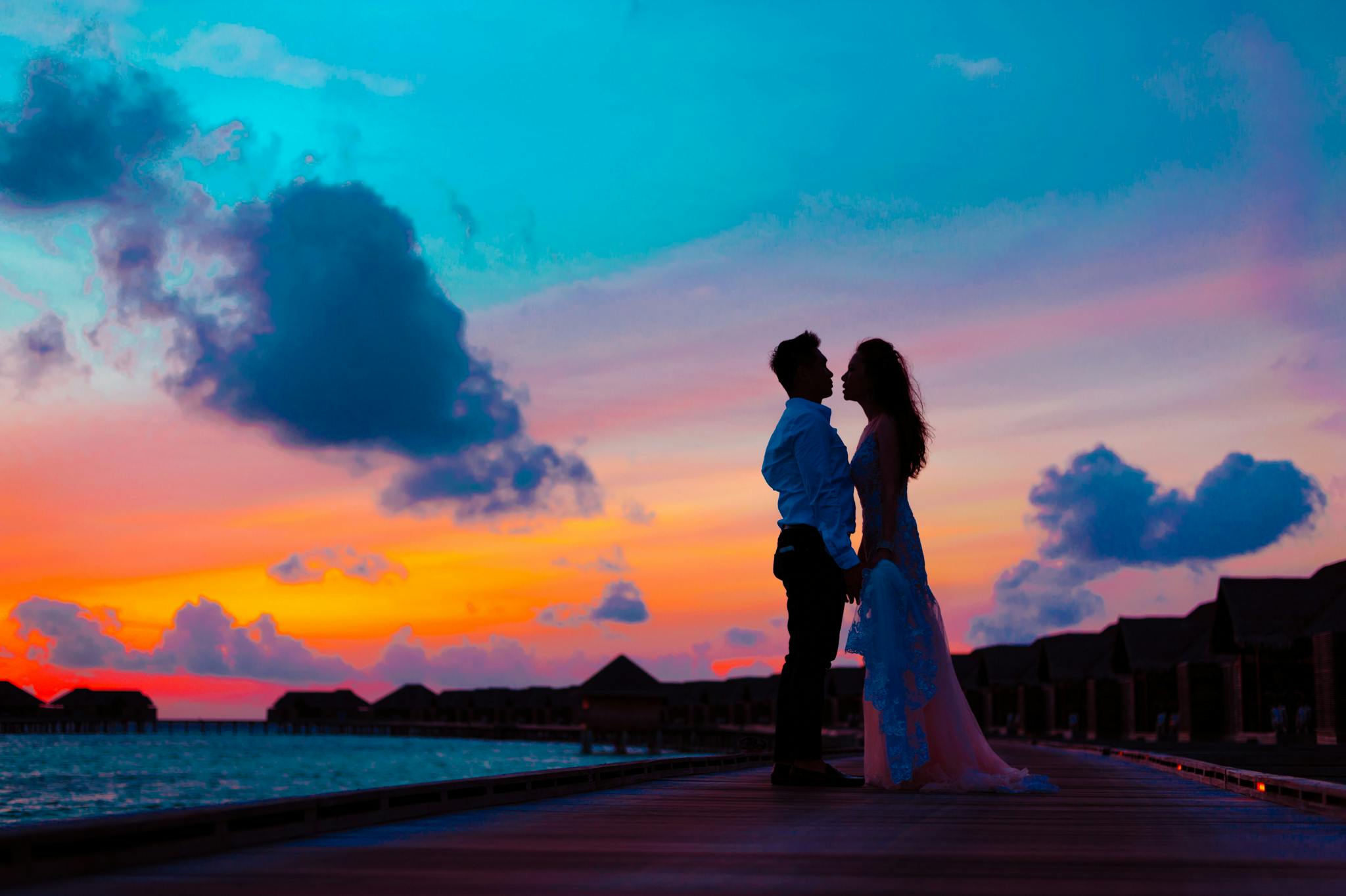 Bride and groom standing on sea dock during golden hour | Source: Pexels