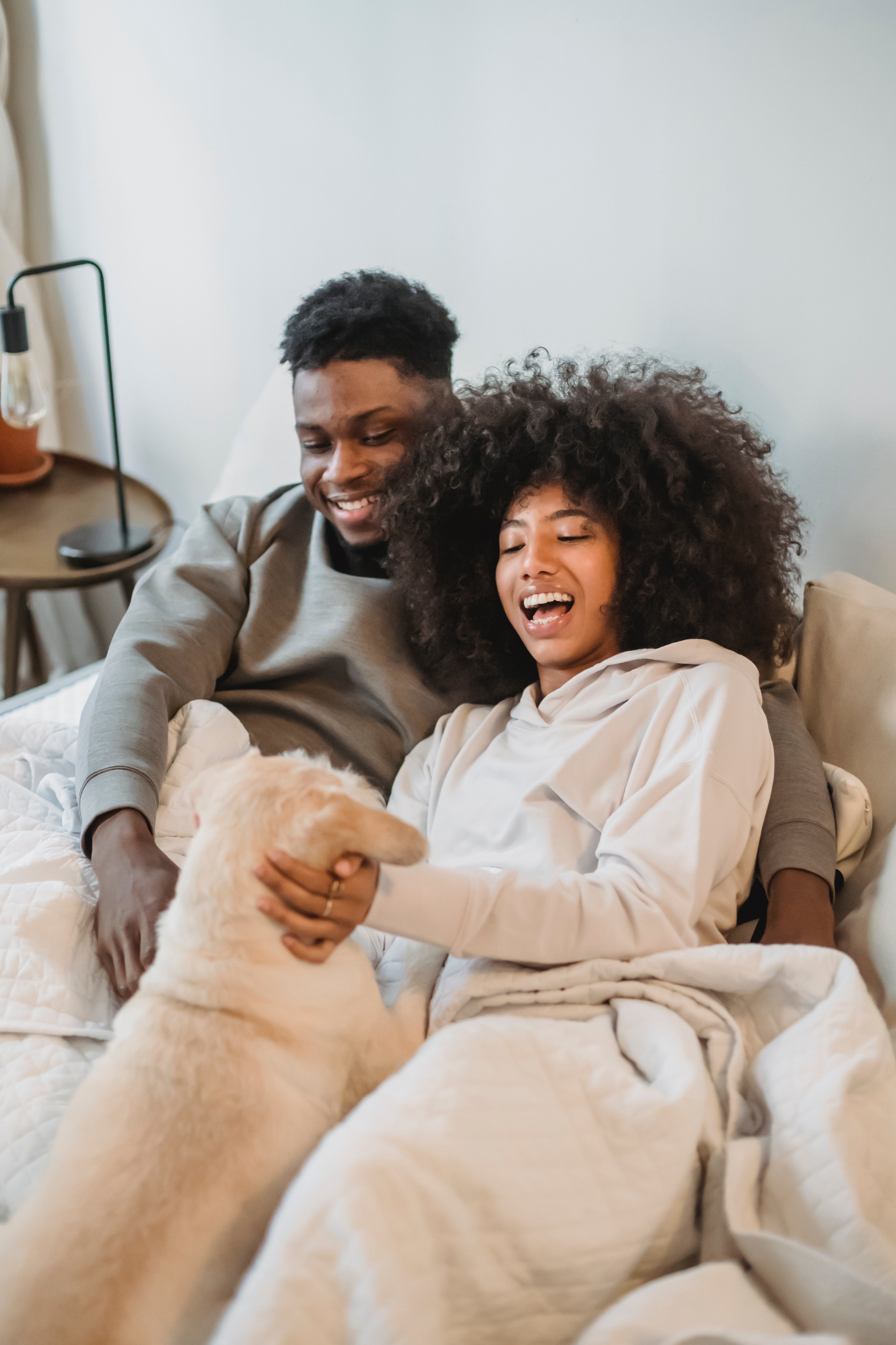 Pictured - A young couple snuggling up with their dog on the bed. | Source: Pexels 