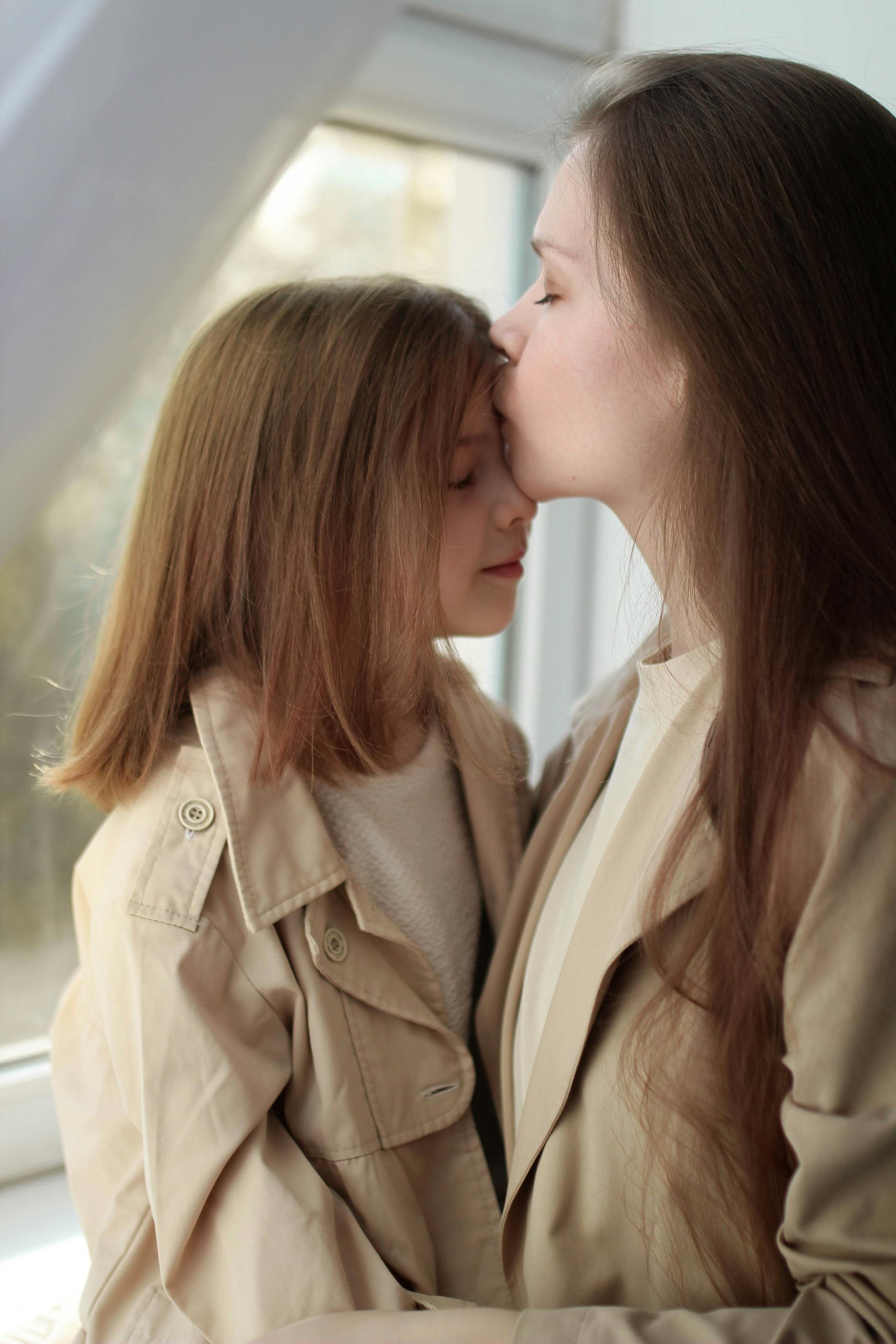 A woman kissing her daughter on the forehead | Source: Pexels