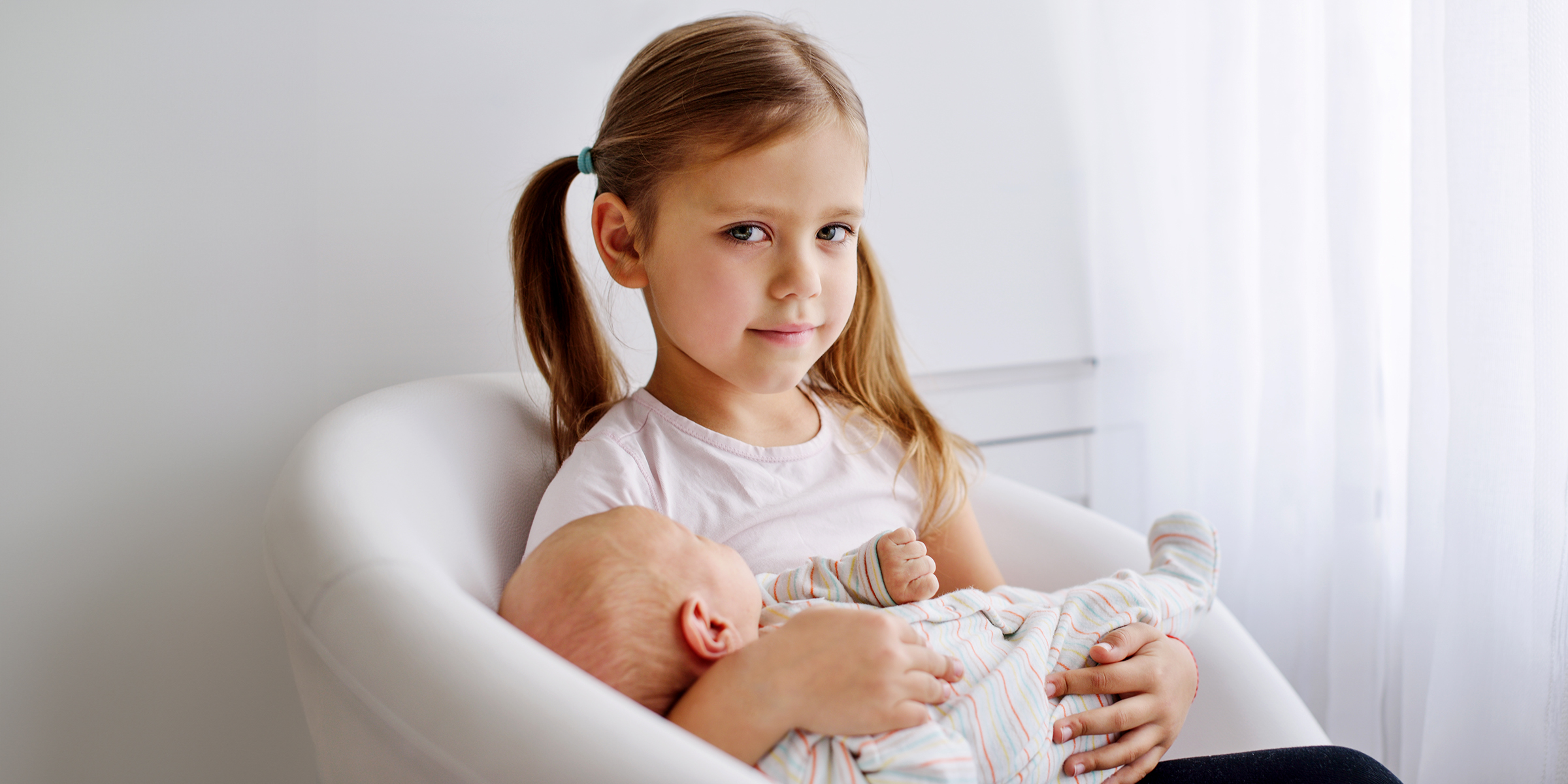 A little girl holding a baby | Source: Shutterstock