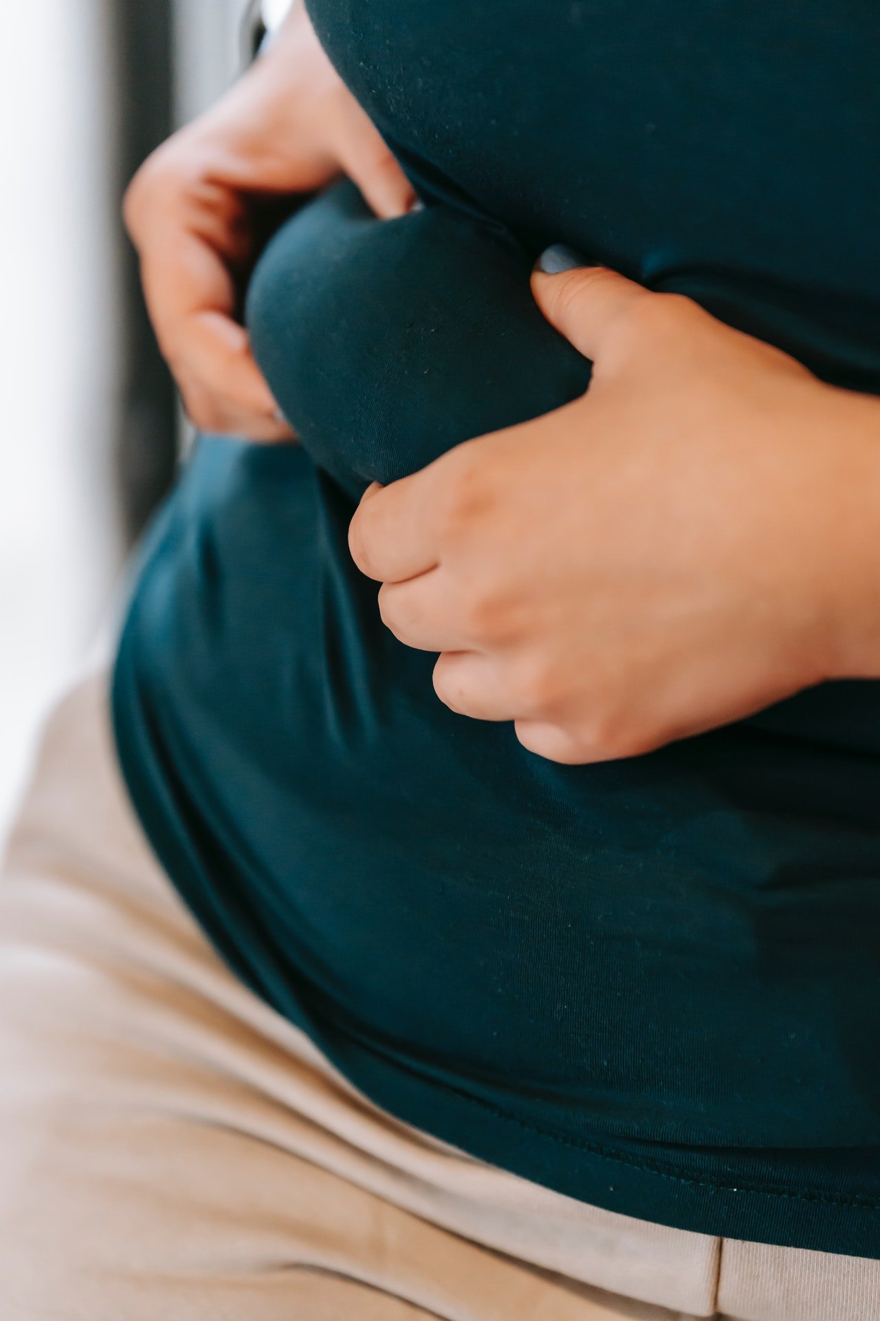Photo of a woman holding her stomach. | Photo: Pexels