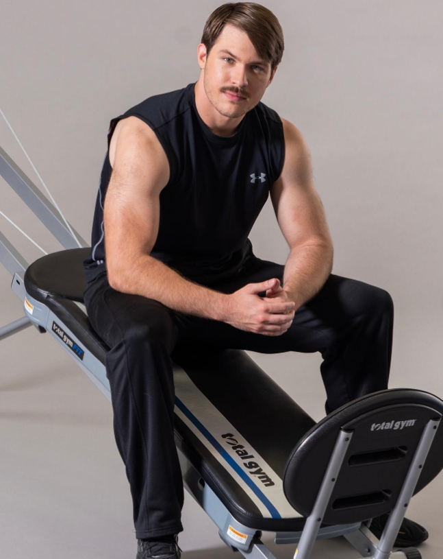 Dakota Norris sits confidently on a Total Gym machine, his athletic build and focused gaze highlighting a fitness-forward presence. | Source: Instagram/d.ak.ot.a