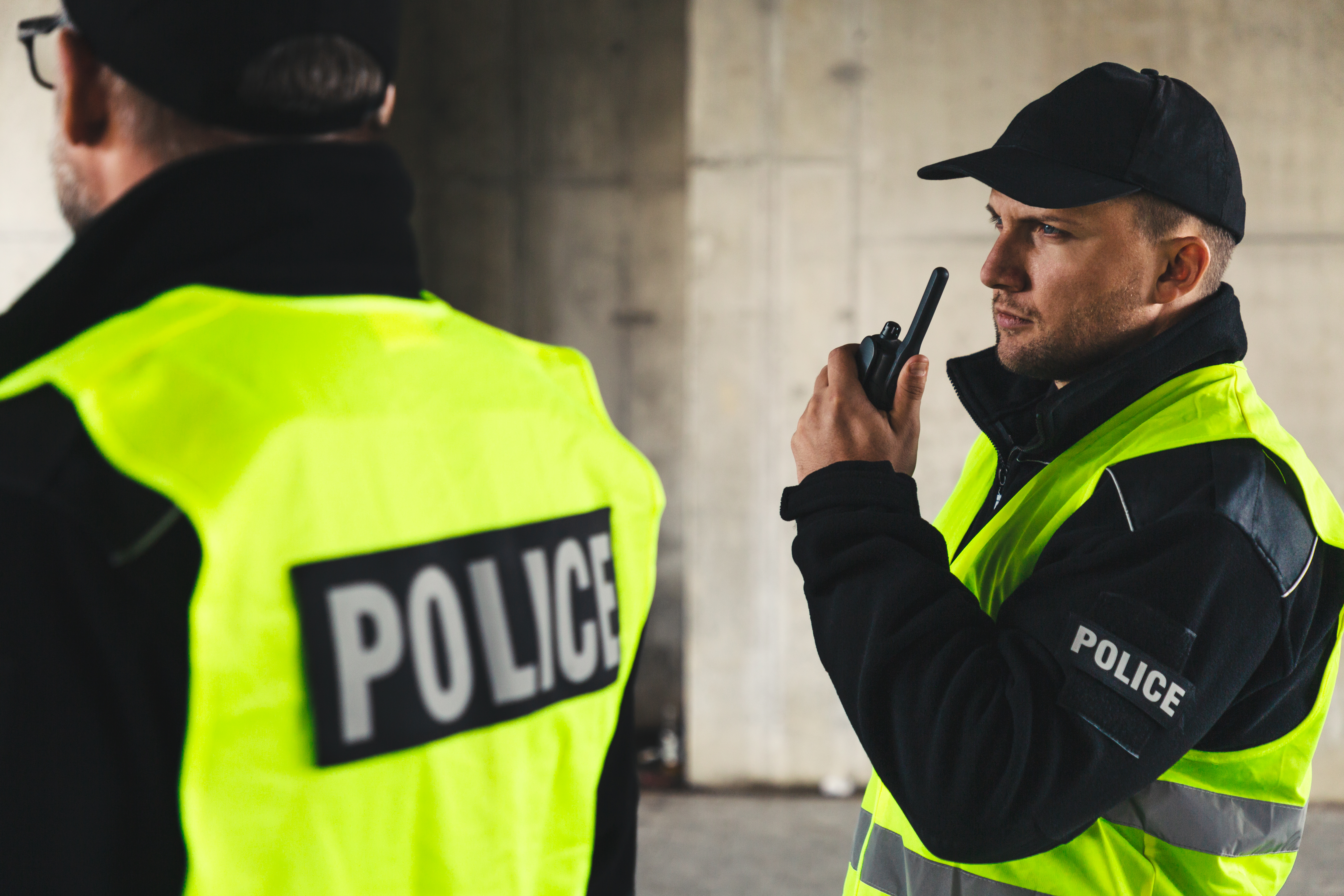 Proud policemen speaking on the walkie-talkie, reporting to station. | Source: Shutterstock