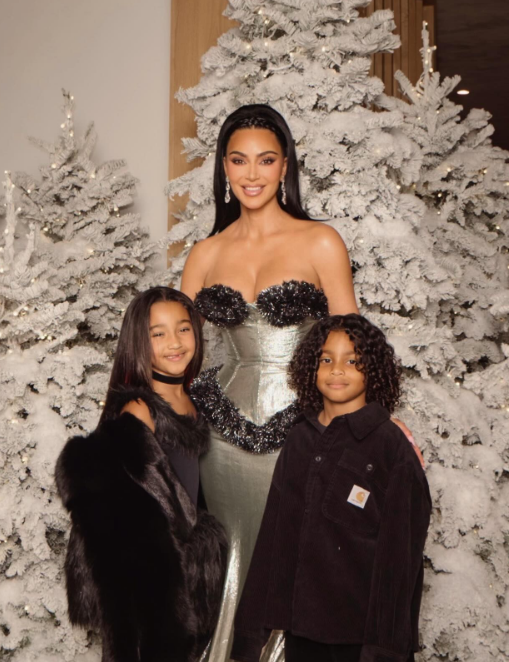 Kim Kardashian and her youngest kids Chicago and Psalm West posing in front of Christmas trees, from a post dated December 27, 2025 | Source: Instagram/kimkardashian