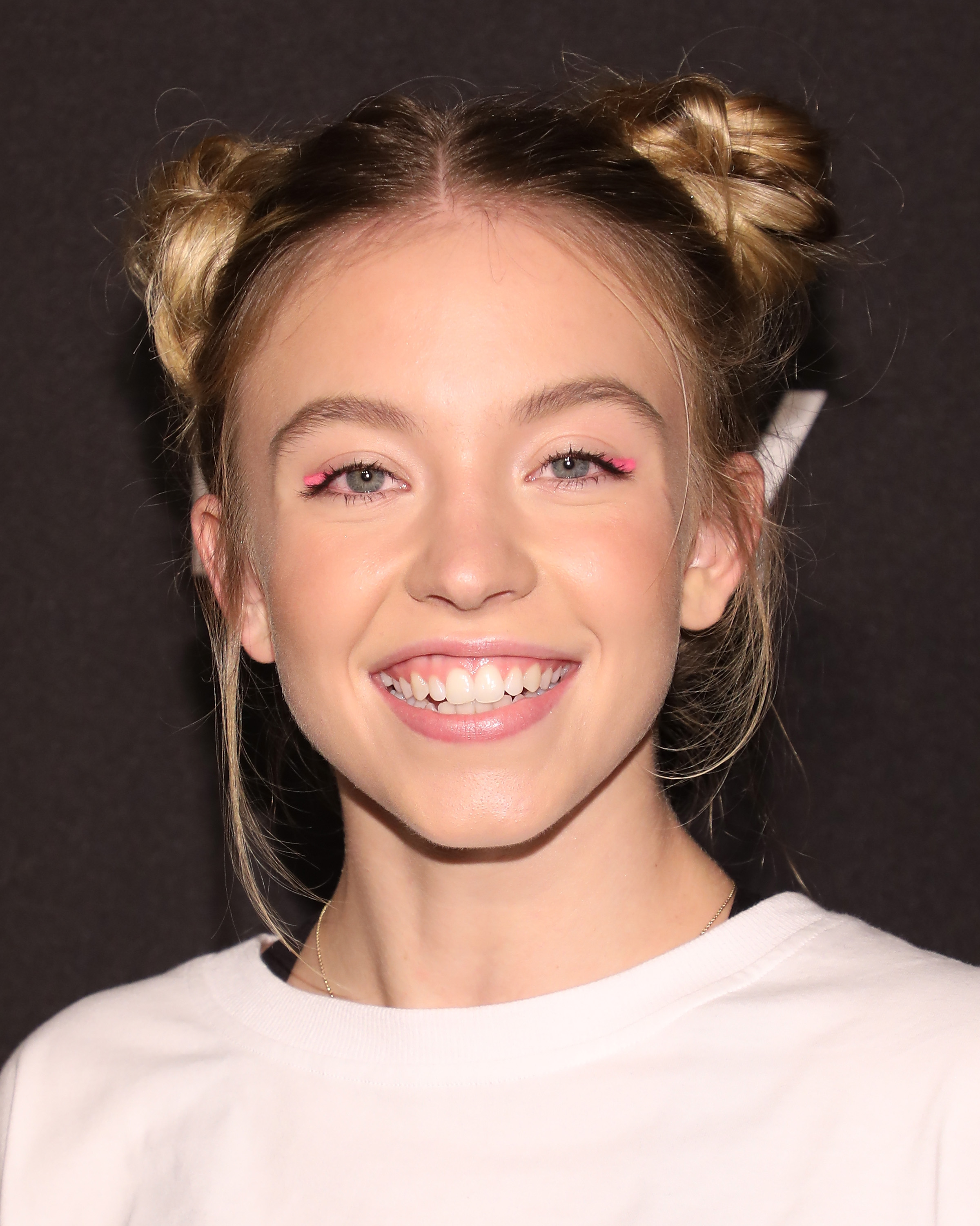Sydney Sweeney embraced a youthful, carefree look at DKNY's 30th anniversary bash in New York, styling her hair in playful double space buns. Her bright pink eyeshadow added a fun twist to her laid-back top and infectious smile.