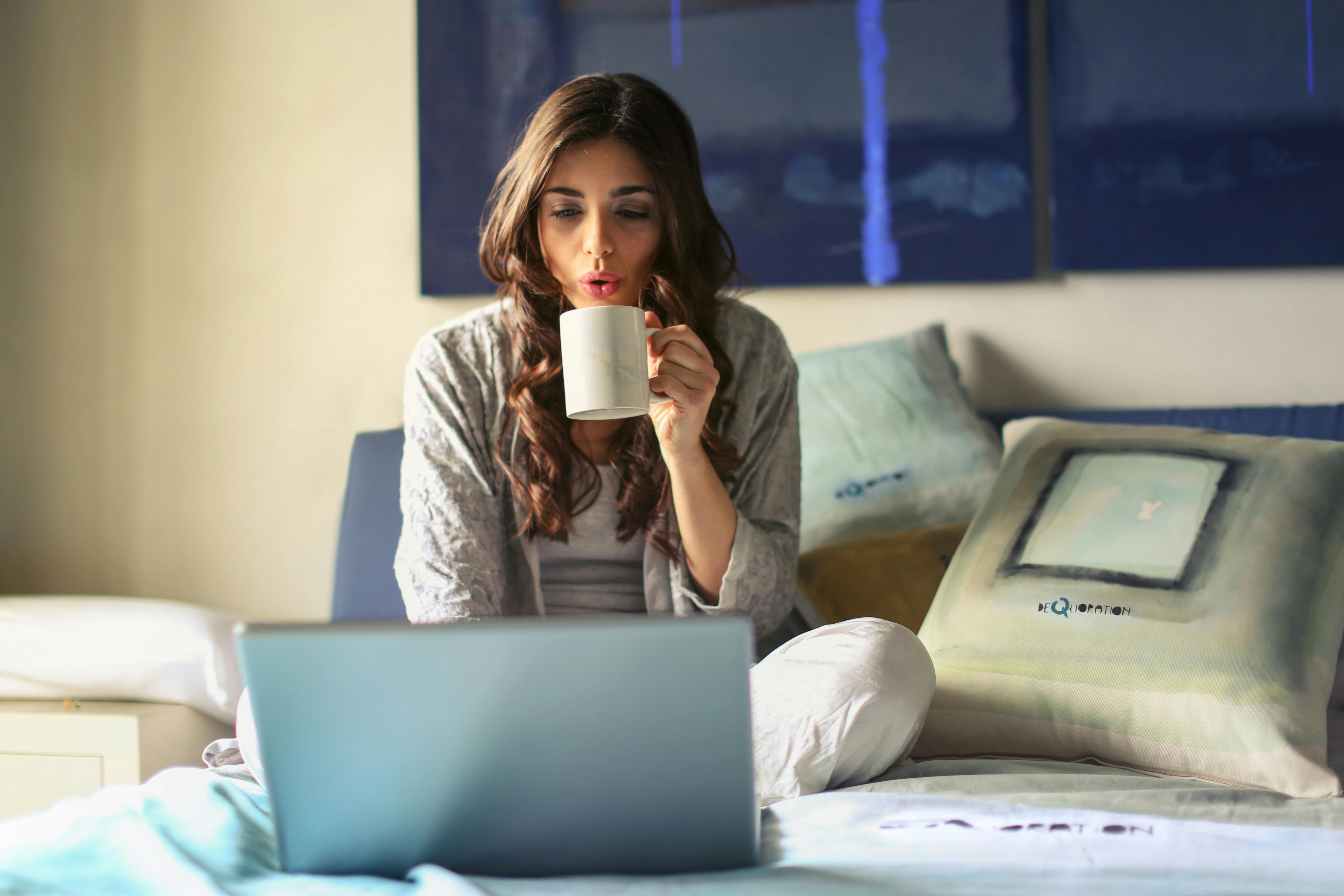 Woman drinks tea in front of laptop | Source: Pexels
