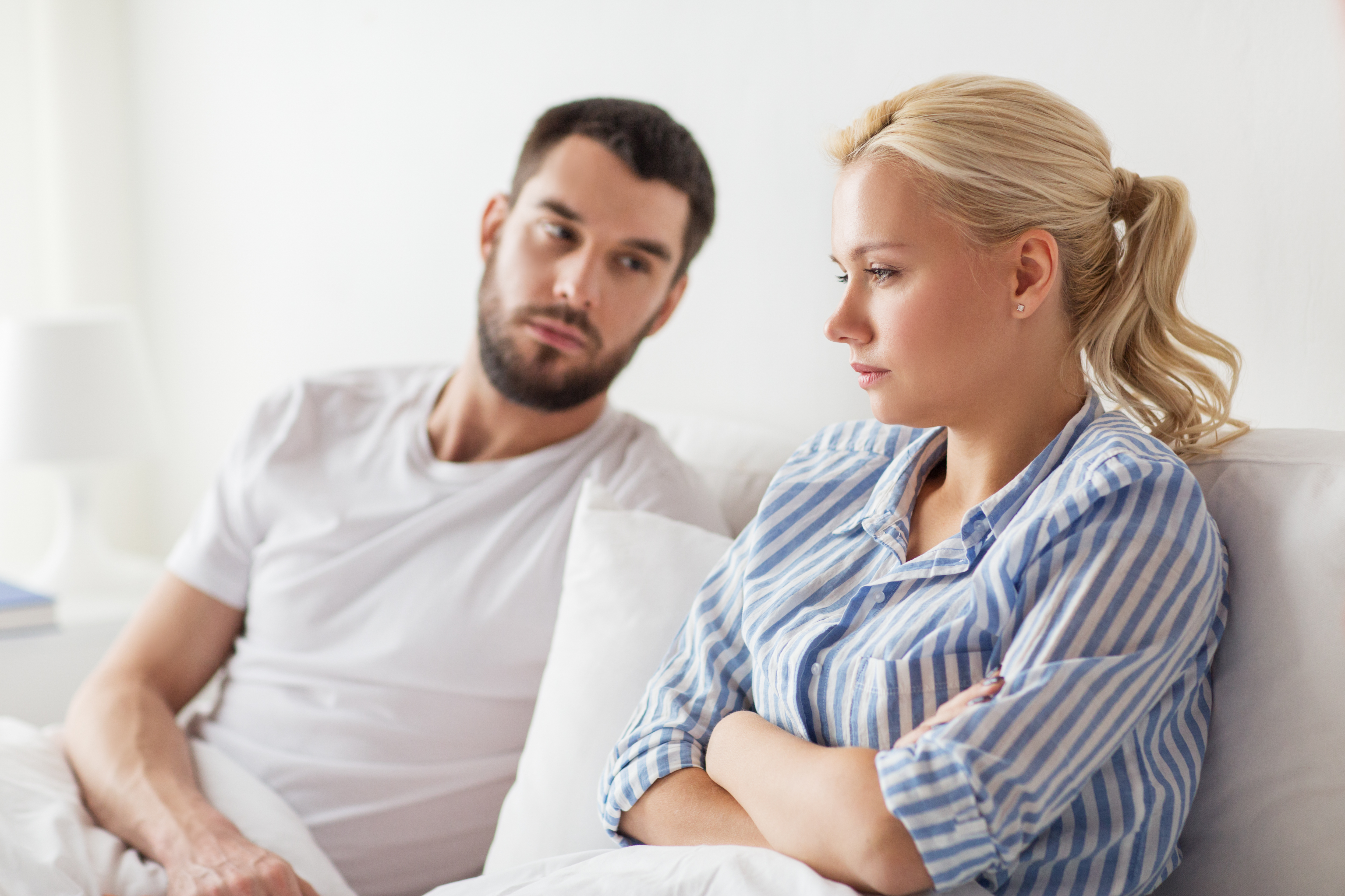 An upset woman with an apologetic looking man seated beside her | Source: Shutterstock