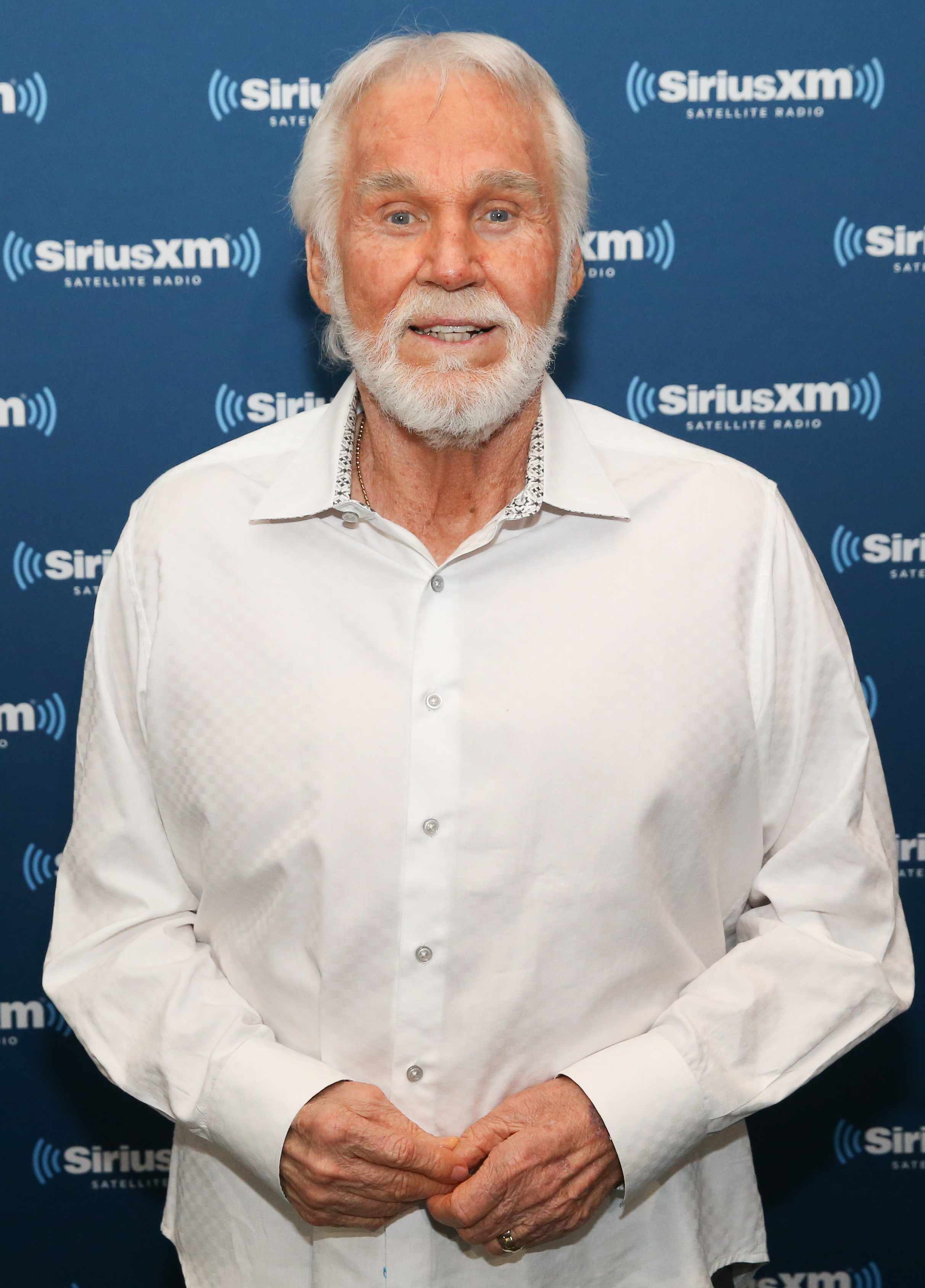 Kenny Rogers attends SiriusXM's "Town Hall" at the Music City Theatre in Nashville on June 8, 2017, looking cheerful in front of the SiriusXM backdrop | Source: Getty Images