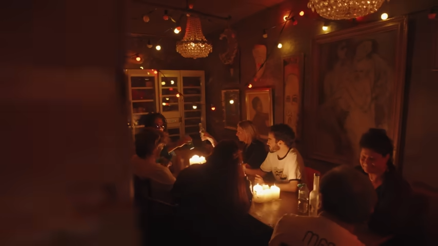Friends gather around a cozy, candlelit bistro table to enjoy drinks and late-night conversation. | Source: YouTube/@Archdigest