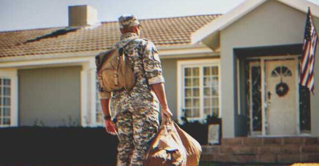 Militar sosteniendo un bolso y mirando hacia una casa | Foto: Shutterstock
