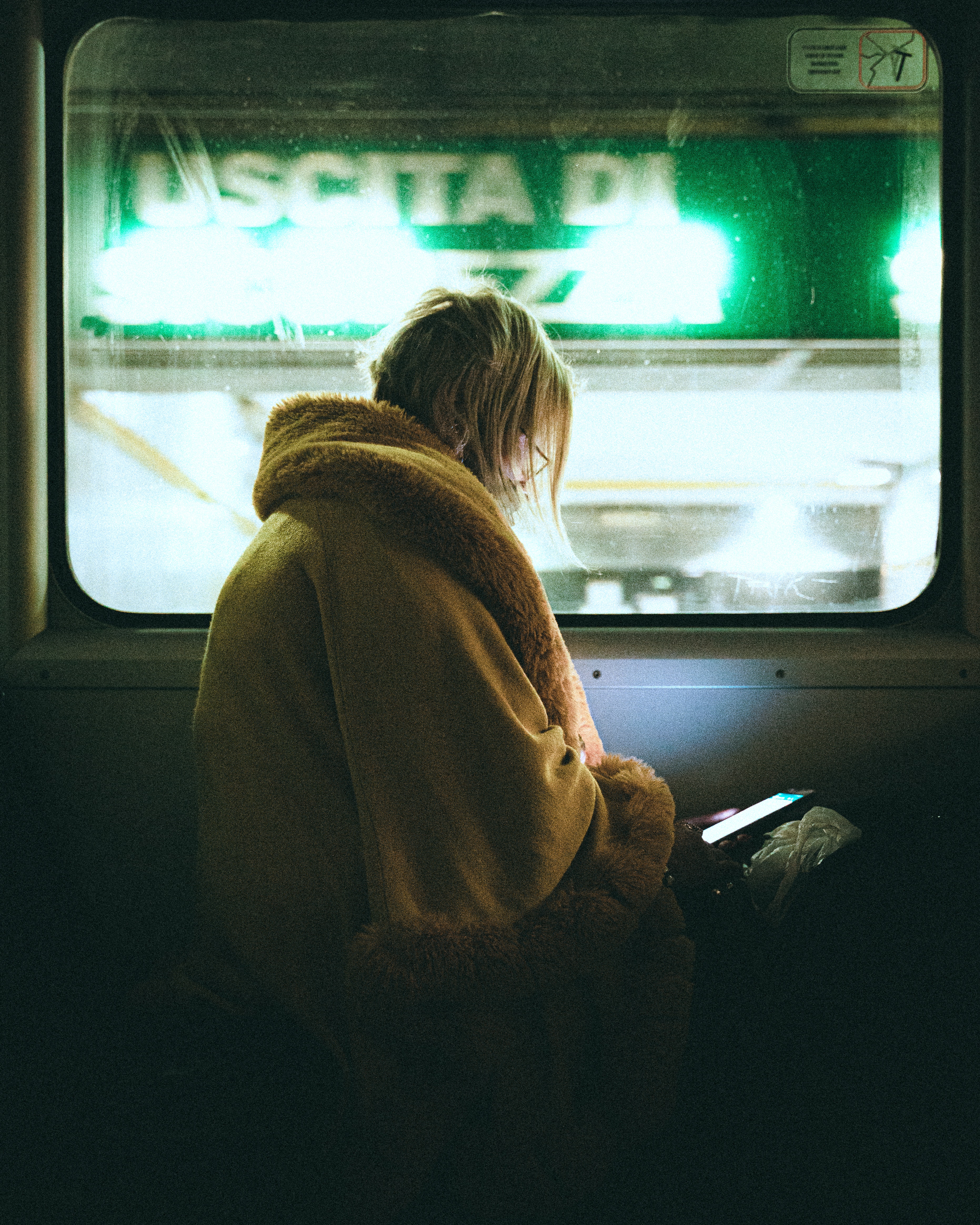 A woman looking at her cellphone in a dark train cabin | Source: Pexels