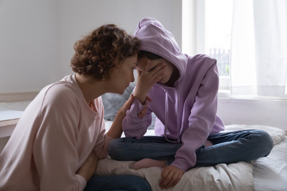 Older woman comforting an upset teenage daughter while bonding at home | Photo: Shutterstock/fizkes