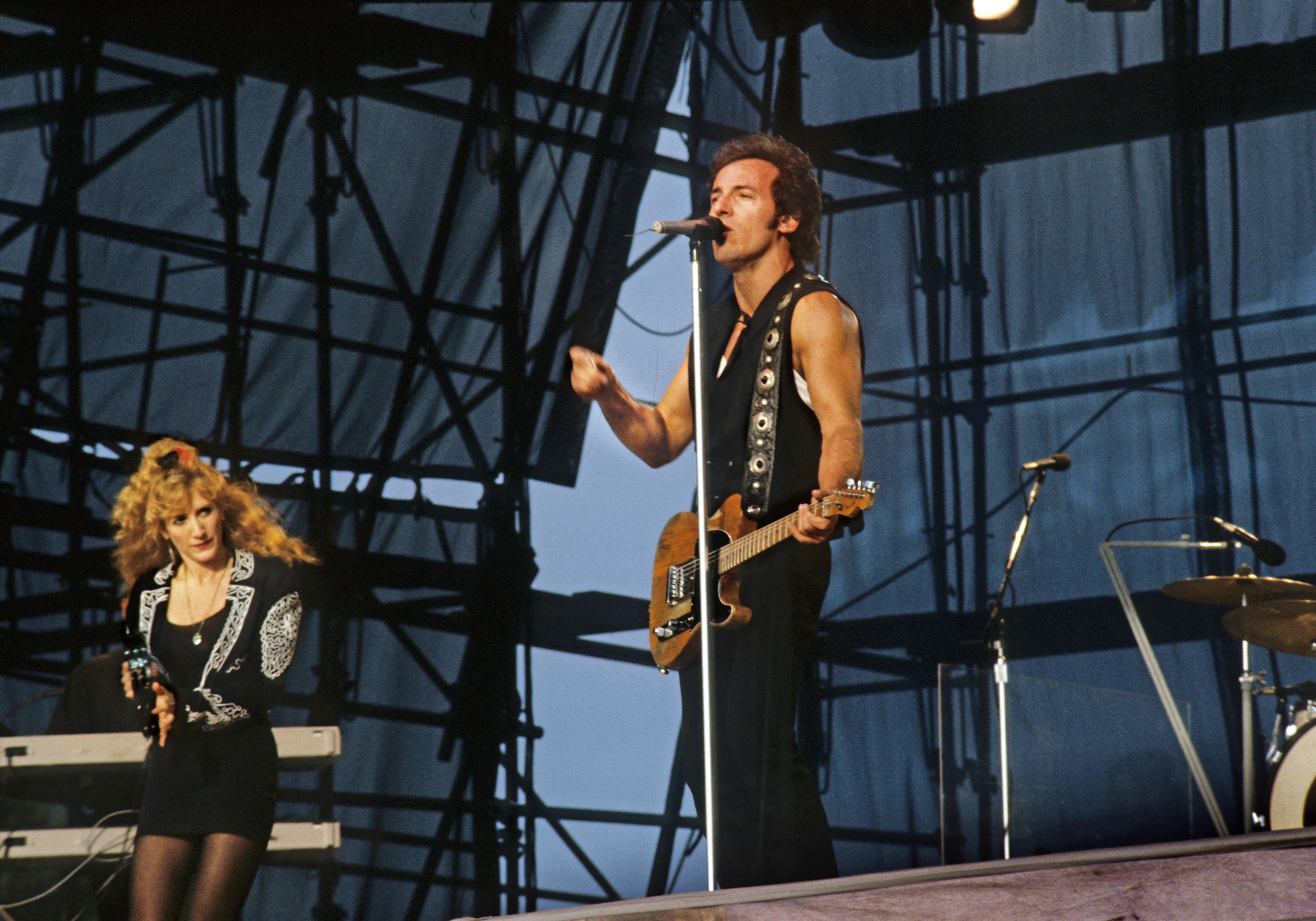 Bruce Springsteen performs live on stage with his wife Patti Scialfa at Berliner Rocksommer in Radstadion Weissensee, Ostberlin, on July 19, 1988. | Source: Getty Images