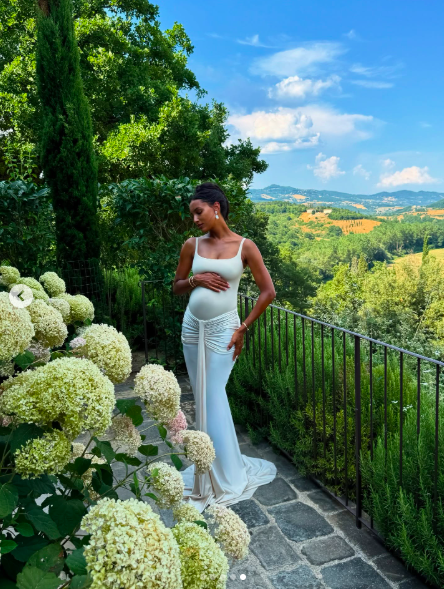 Jasmine Tookes posing against a beautiful countryside backdrop as she cradles her baby bump, posted on July 9, 2025. | Source: Instagram/jastookes