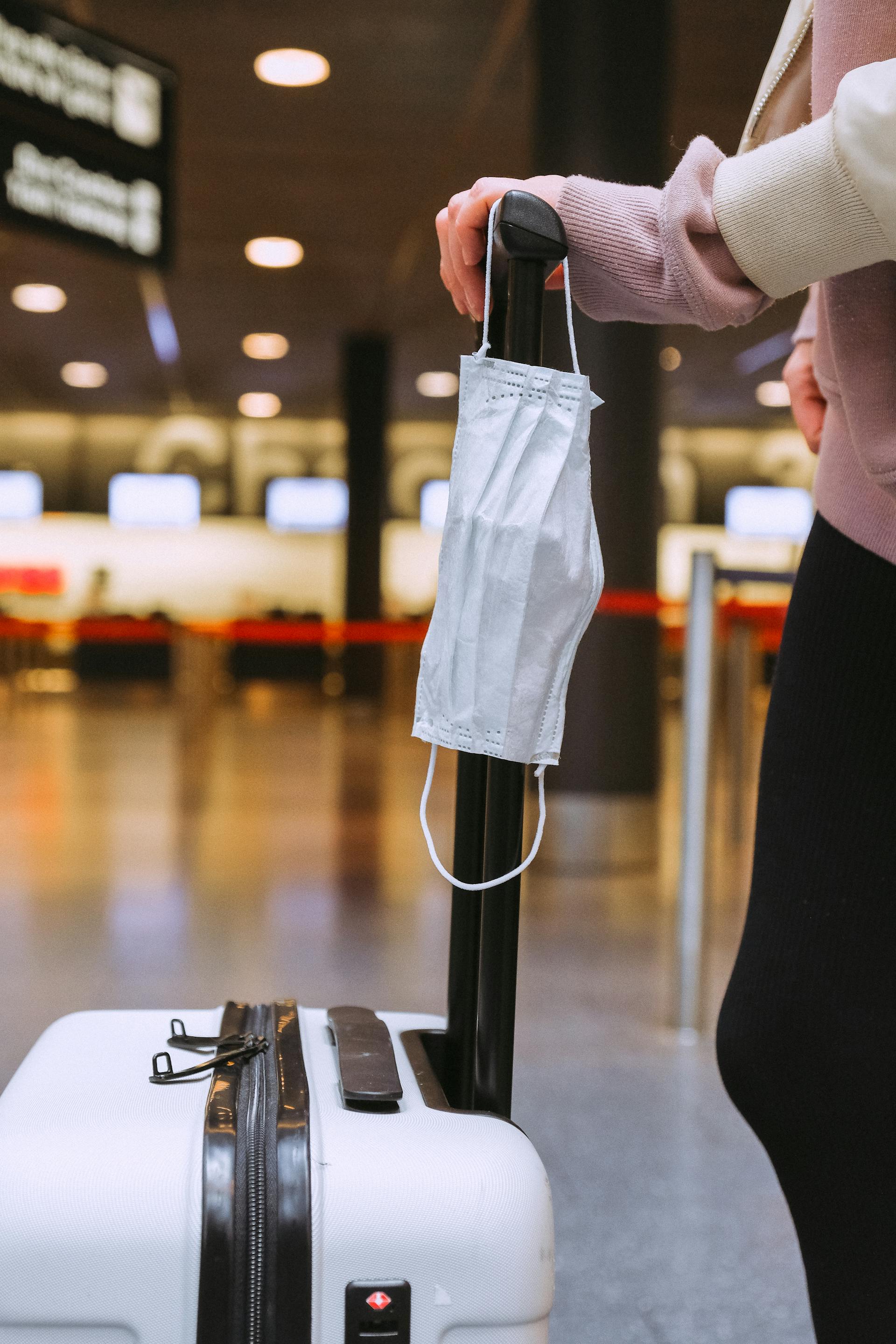 A closeup of a woman holding her suitcase in an airport | Source: Pexels