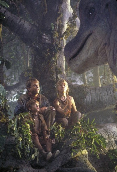 Schauspieler Sam Neill als Dr. Alan Grant, mit Ariana Richards (rechts) und Joseph Mazzello (links) als Lex und Tim, die von einem neugierigen Brachiosaurus angesprochen werden, in einer Szene aus dem Film "Jurassic Park", 1993 | Quelle: Getty Images