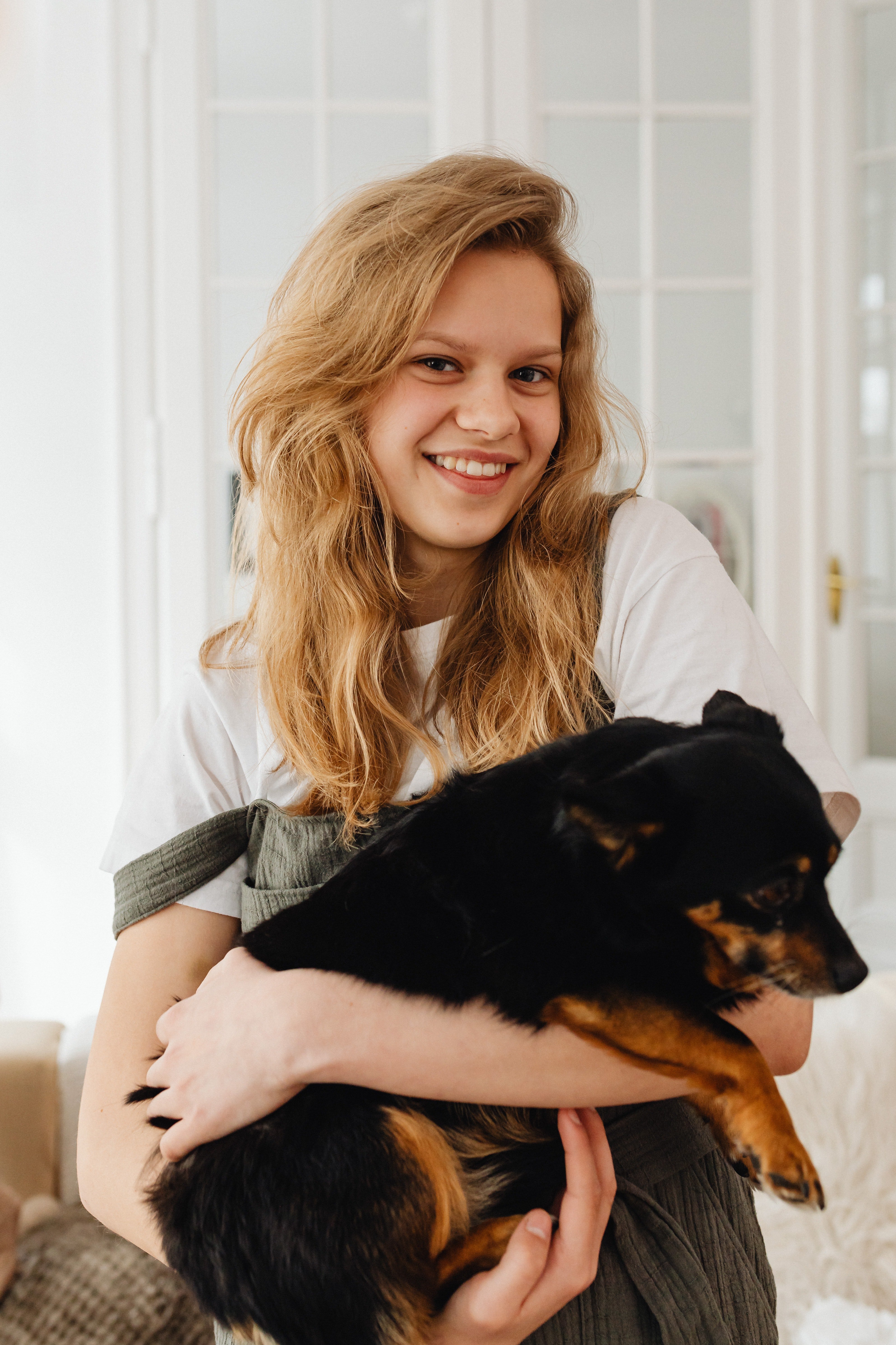 Una chica con un perro en sus brazos. | Pexels