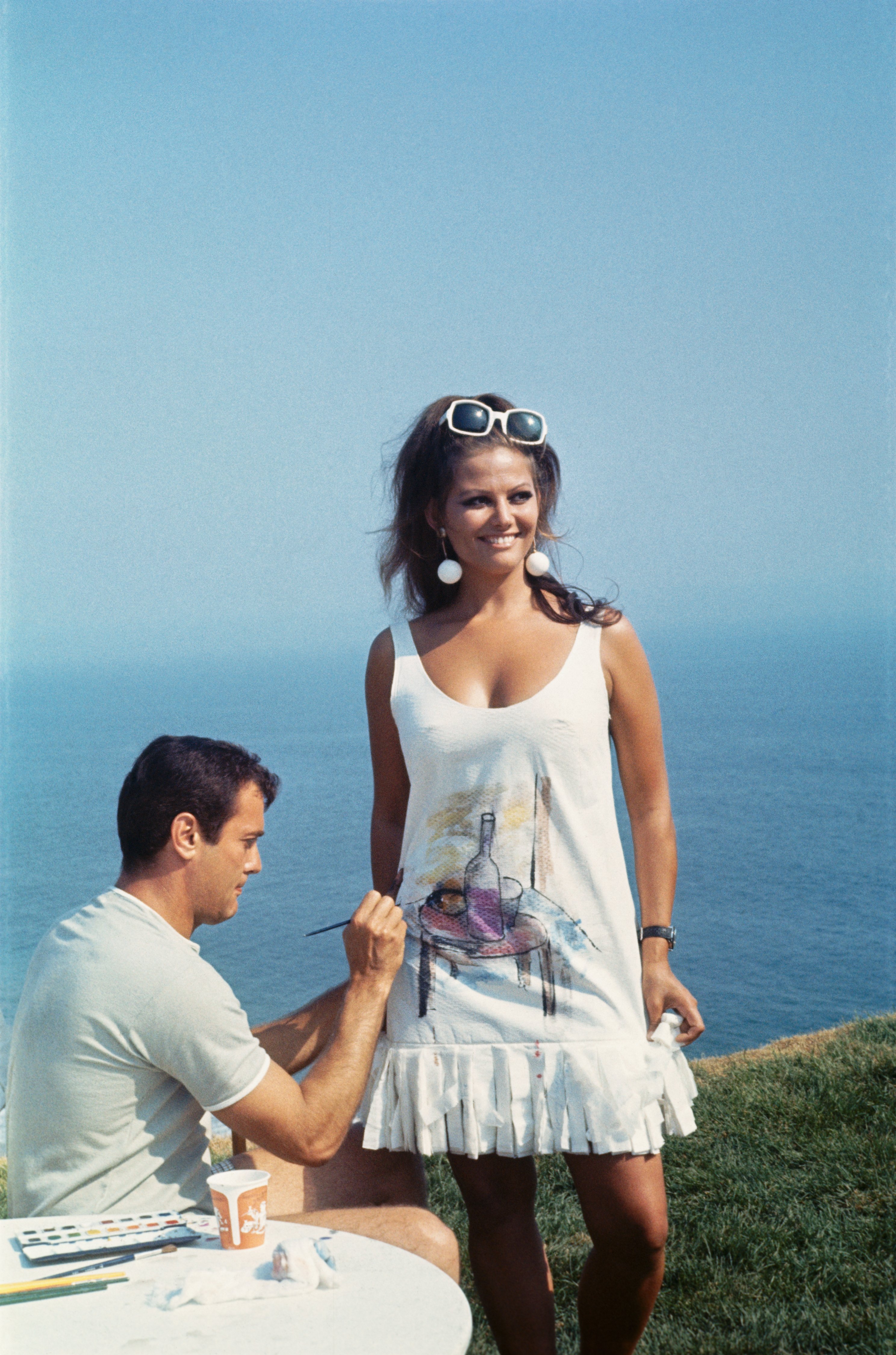 Tony Curtis pinta el vestido de papel de Claudia Cardinale en el set de filmación de la película de 1967, "Don't Make Waves", en California. | Foto: Getty Images Tony Curtis pinta el vestido de papel de Claudia Cardinale en el set de filmación de la película de 1967, "Don't Make Waves", en California. | Foto: Getty Images